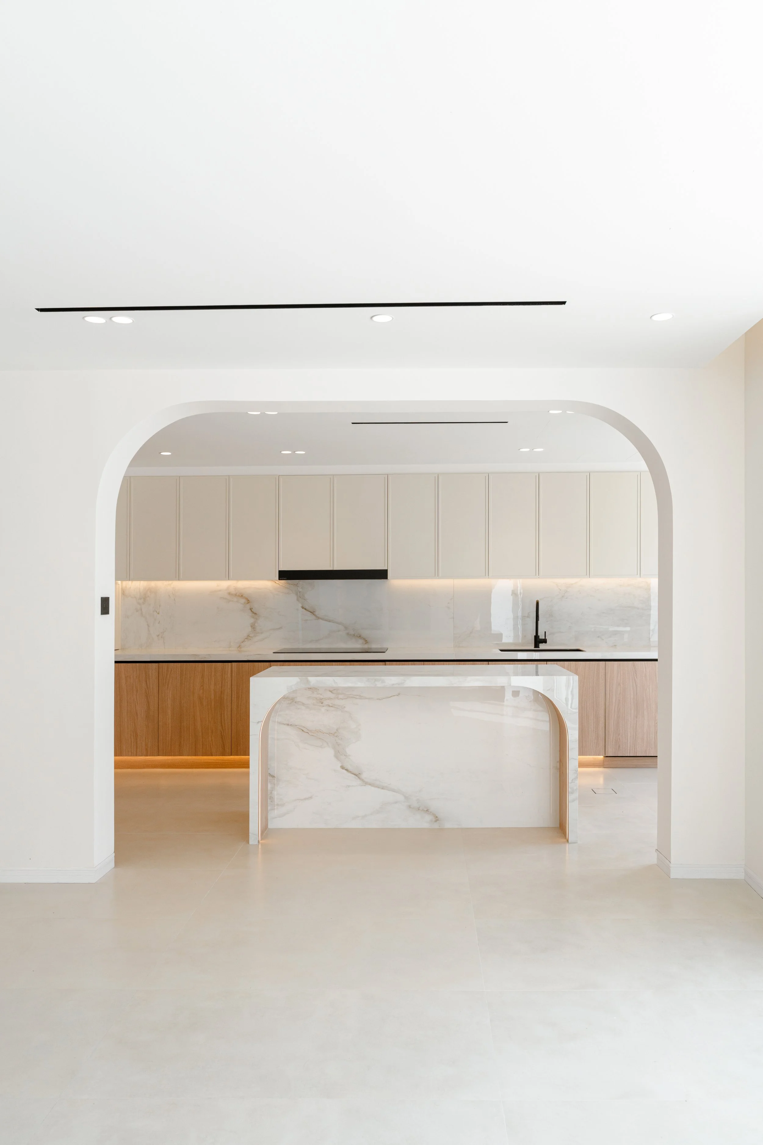 Bright villa kitchen with marble island, arched opening and neutral interior finishes