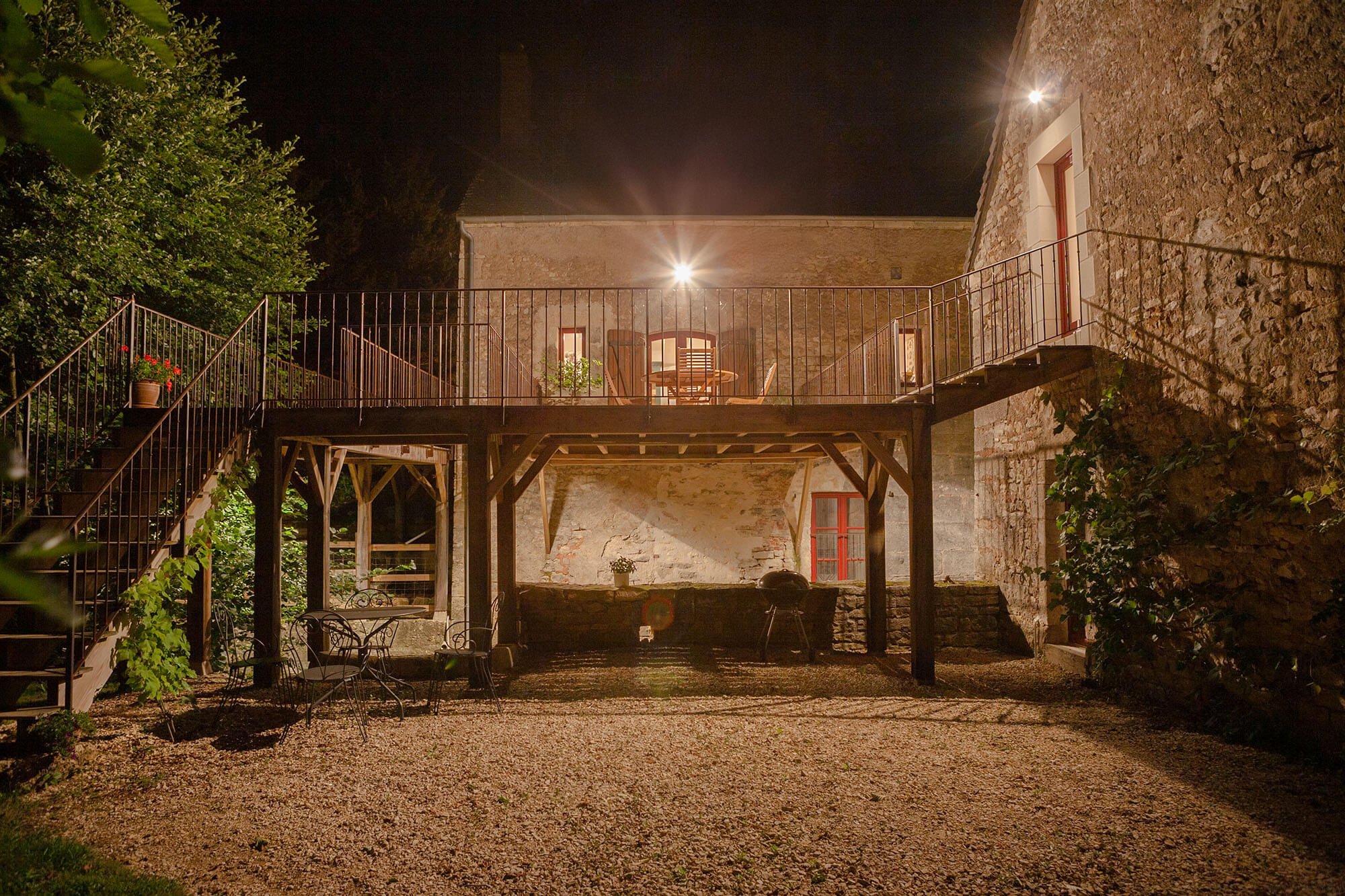Nighttime photograph of an illuminated elevated terrace with dining furniture at the historic Rix Mill in Burgundy