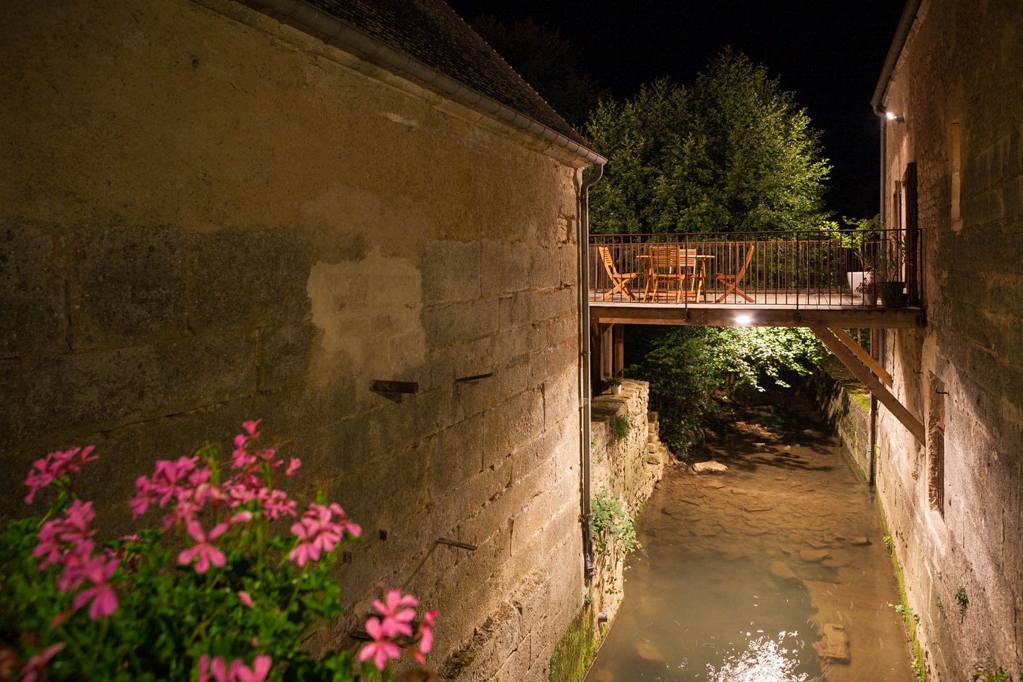 Terrace of the gîte at night, with views over the gently flowing mill stream, creating a tranquil evening atmosphere in Rix.