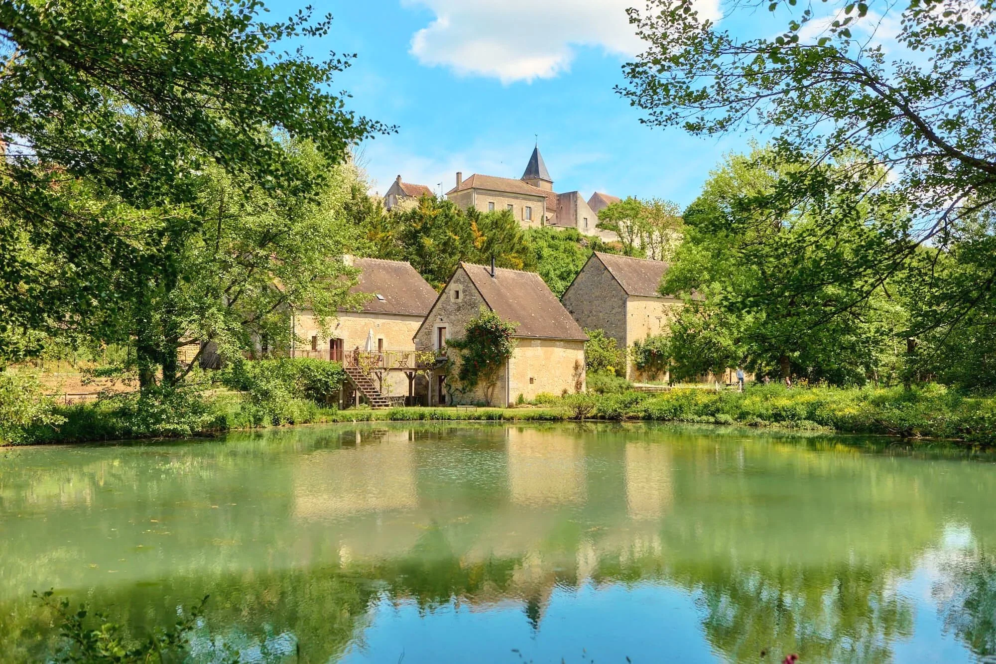 iew across the lake showing the mill ensemble with the gîte at the centre and the village of Rix on the hillside behind, Burgundy.