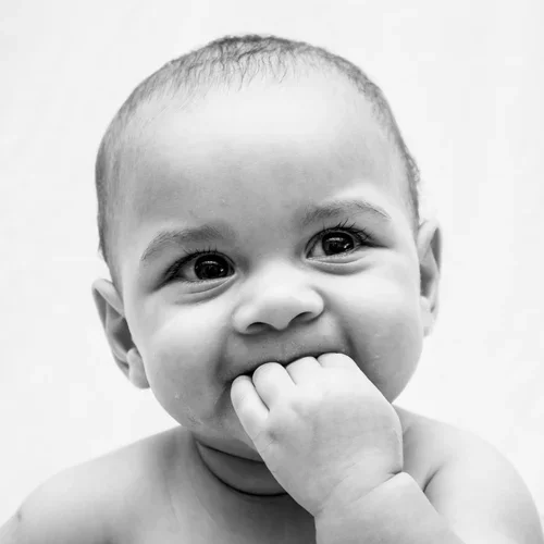 Black and white photo, baby with hand in mouth