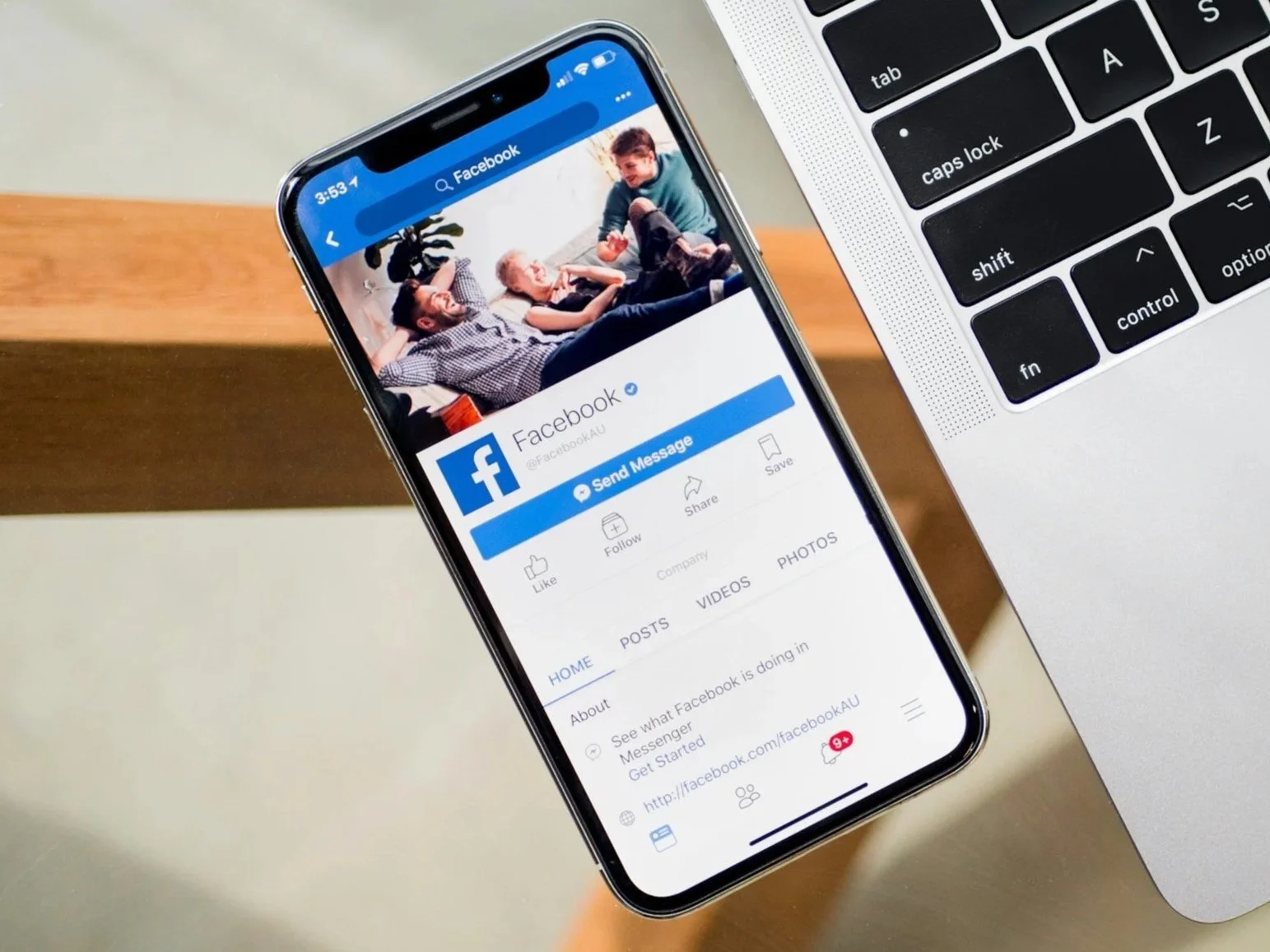 A smartphone displaying the Facebook app next to a laptop on a wooden table displaying Polaar Media's Services