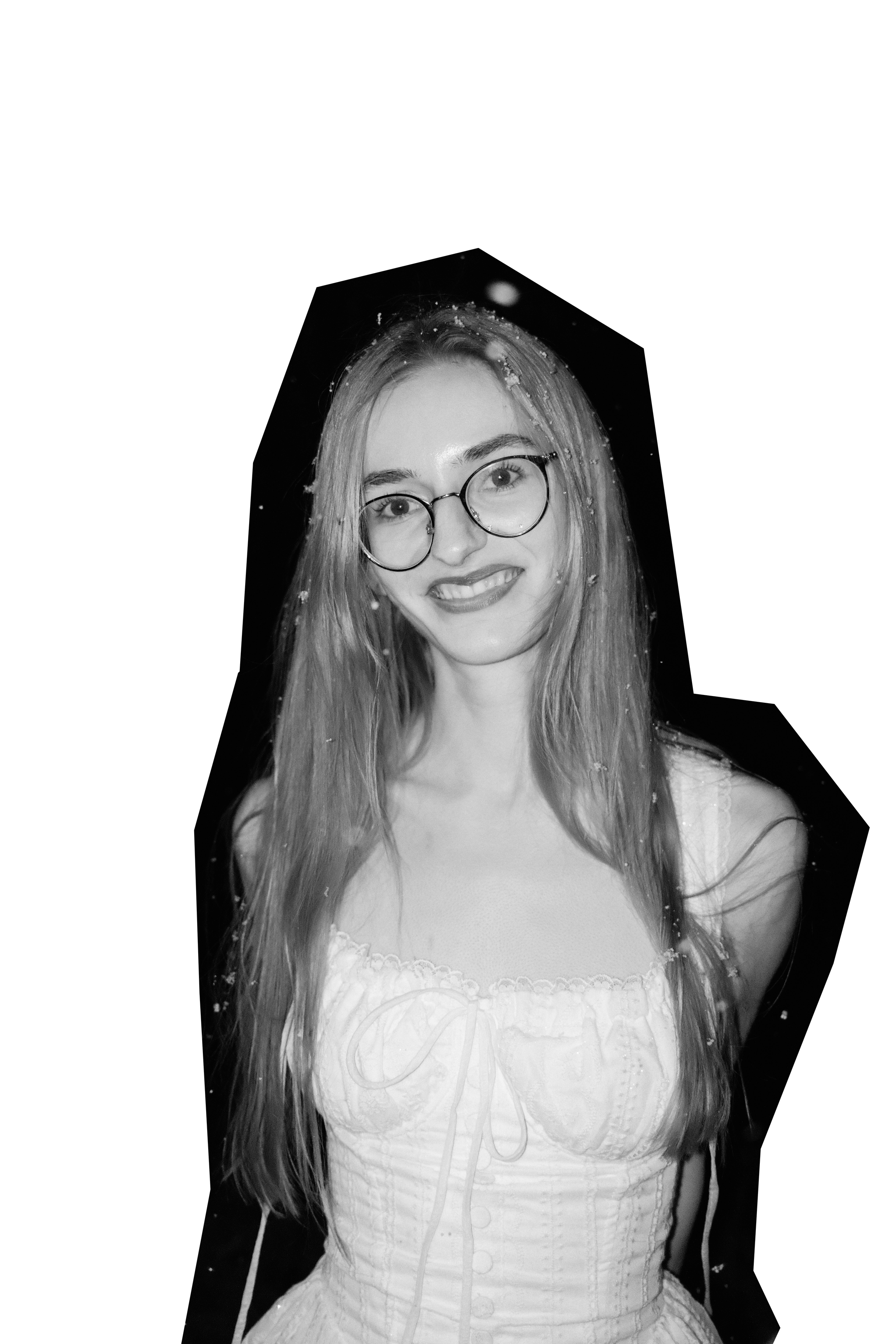 Schwarz-Weiß-Fotografie eines lachenden jungen Mädchens (Jasmin Peter) mit langen Haaren, Brille und lockerer Kleidung, vor einem dunklen Hintergrund.