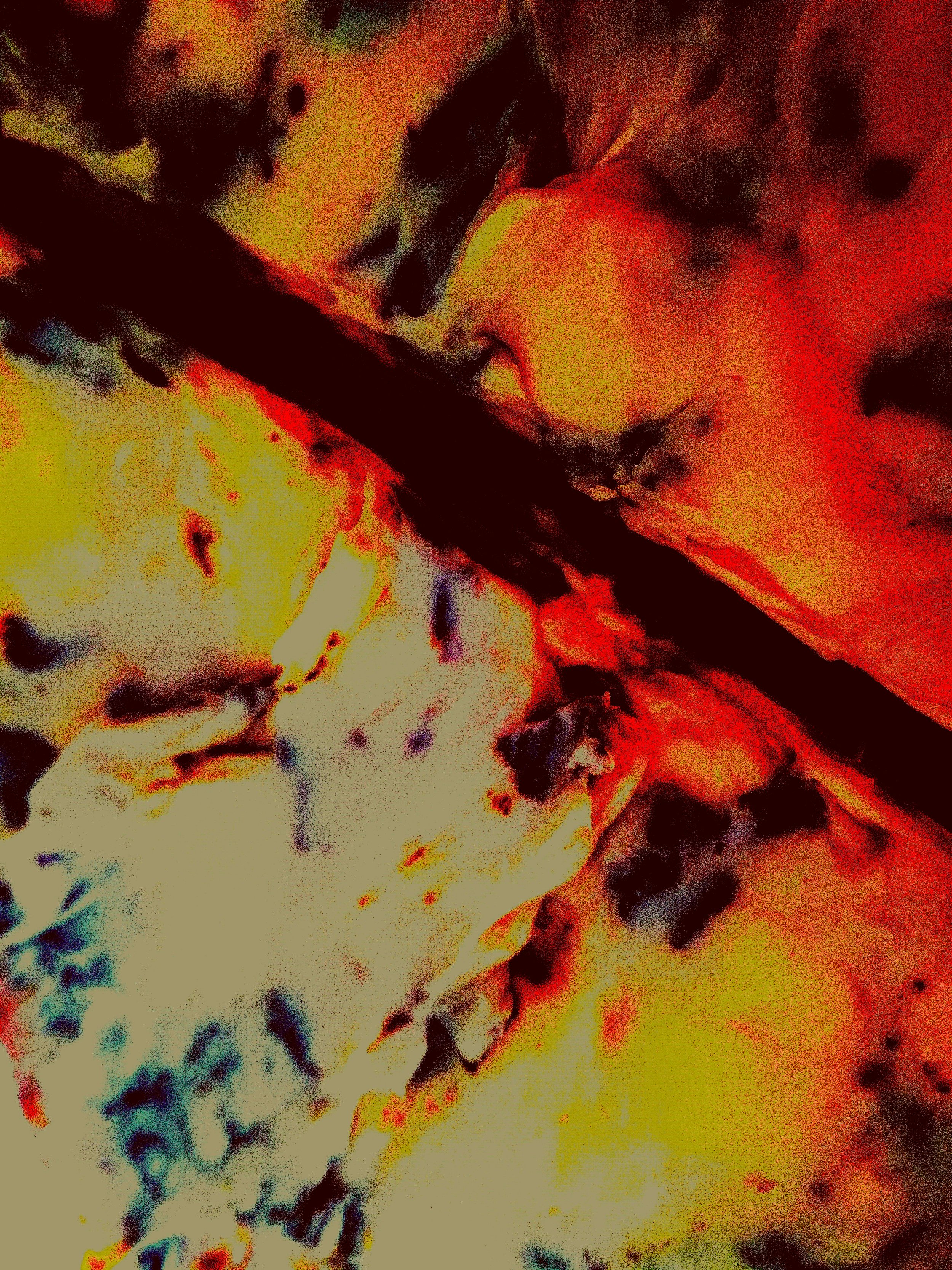 Abstract, colorful image with red, yellow, black, white, and blue hues, resembling a close-up of a fiery or molten surface.