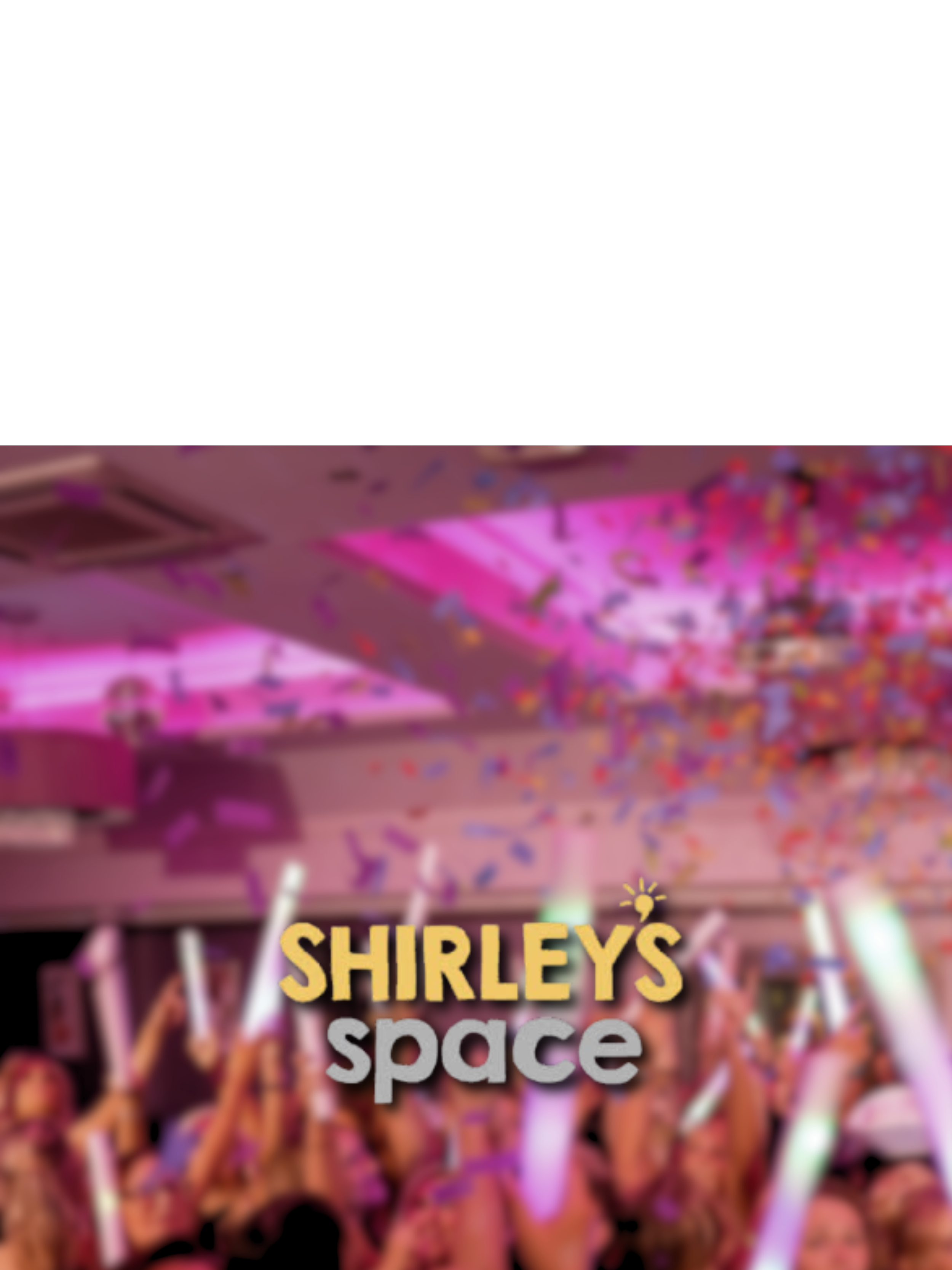 Crowd of people celebrating at a party with confetti and glow sticks under pink and purple lighting.