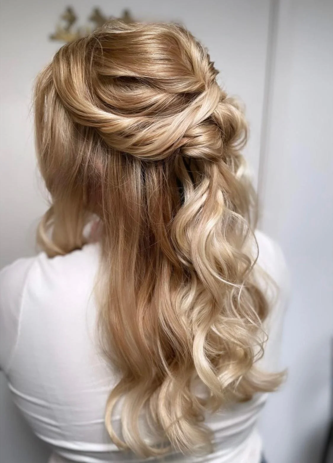 Woman with blonde, curled hairstyle with an elegant twist at the crown of her head.