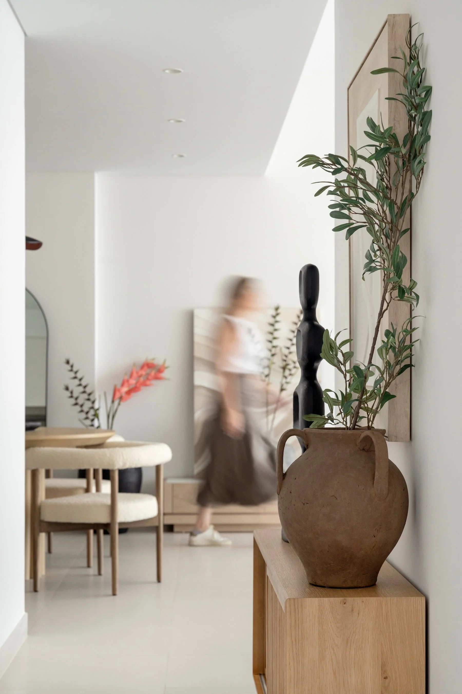 Decorative pottery vase with green leafy branch on a wooden side table in modern interior