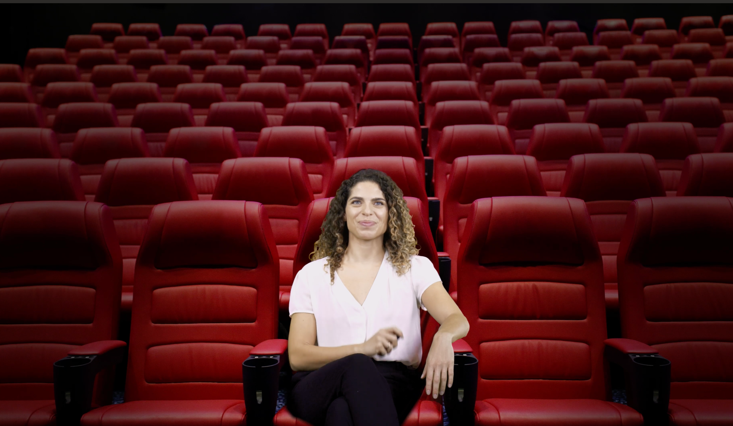 Une femme assise dans une salle de cinéma regarde un film projeté sur un écran
