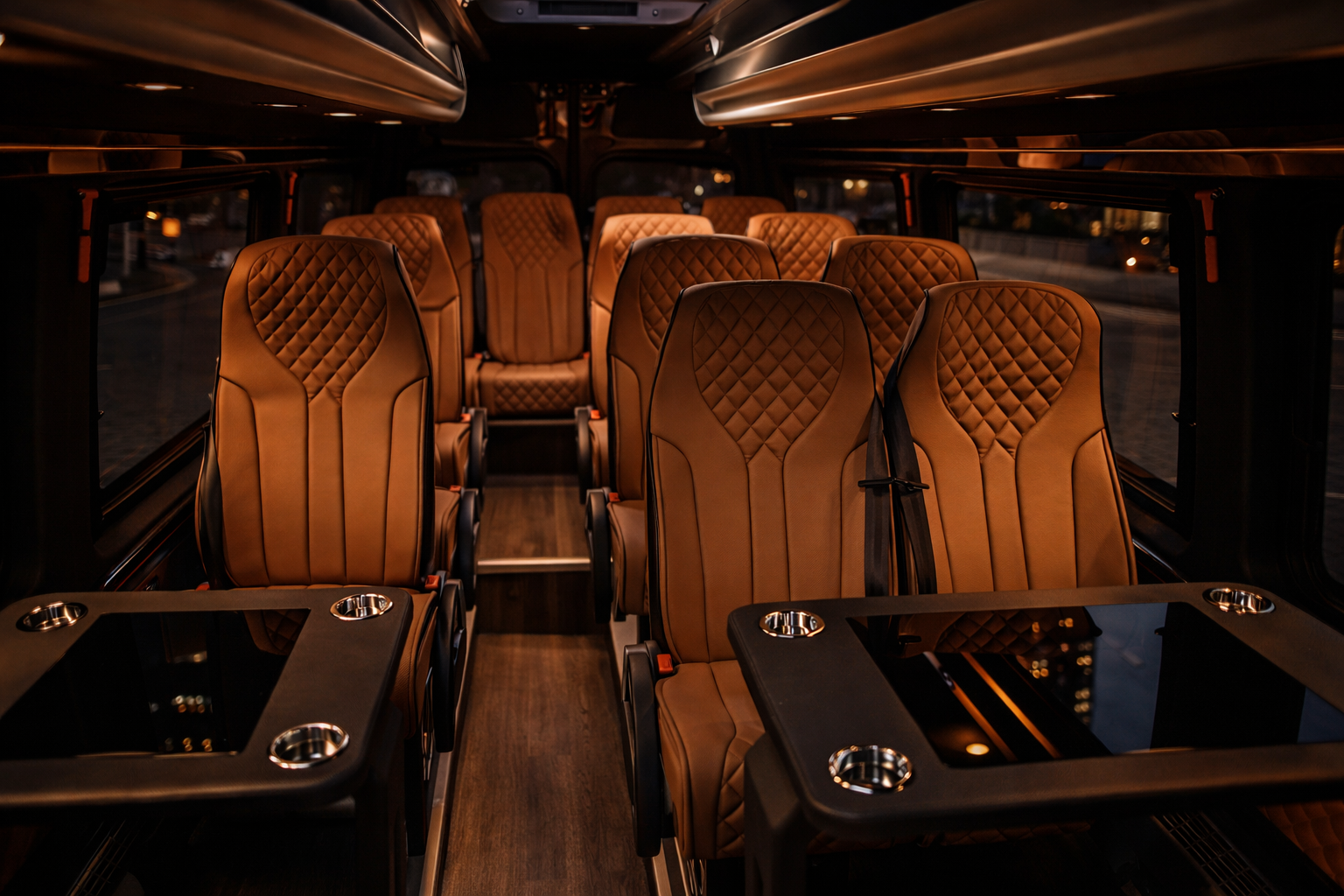 Interior of a luxury bus with tan quilted leather seats and black tables with built-in cup holders