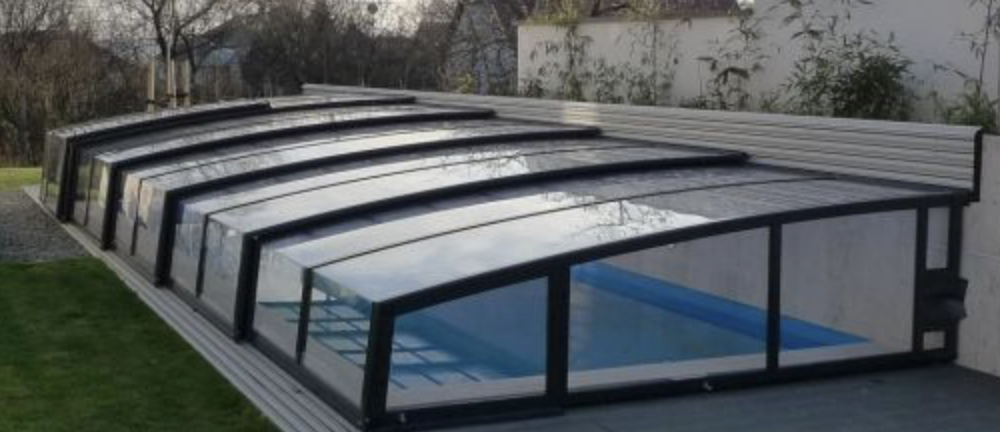 CORNER típusú fali rögzítésű eltolható medencefedés modern családi ház oldalához csatlakoztatva.