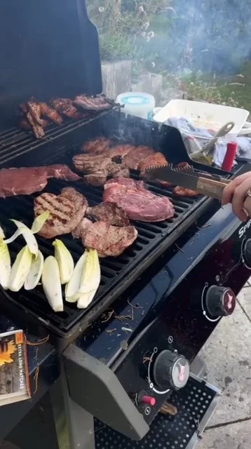 Meat and vegetables grilling on a barbecue grill outdoors.