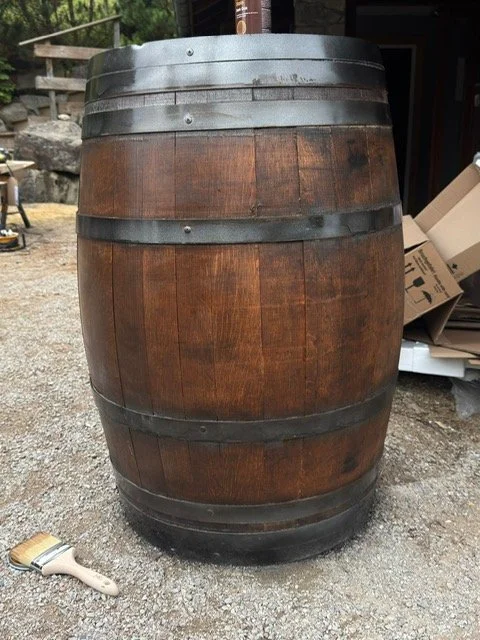 A wooden barrel with metal hoops on an outdoor concrete surface.