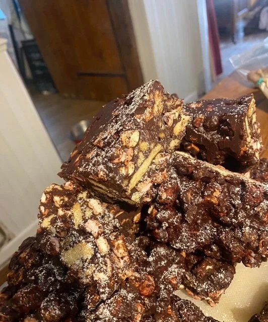 Close-up of multiple homemade chocolate and nut fudge pieces stacked on a surface.