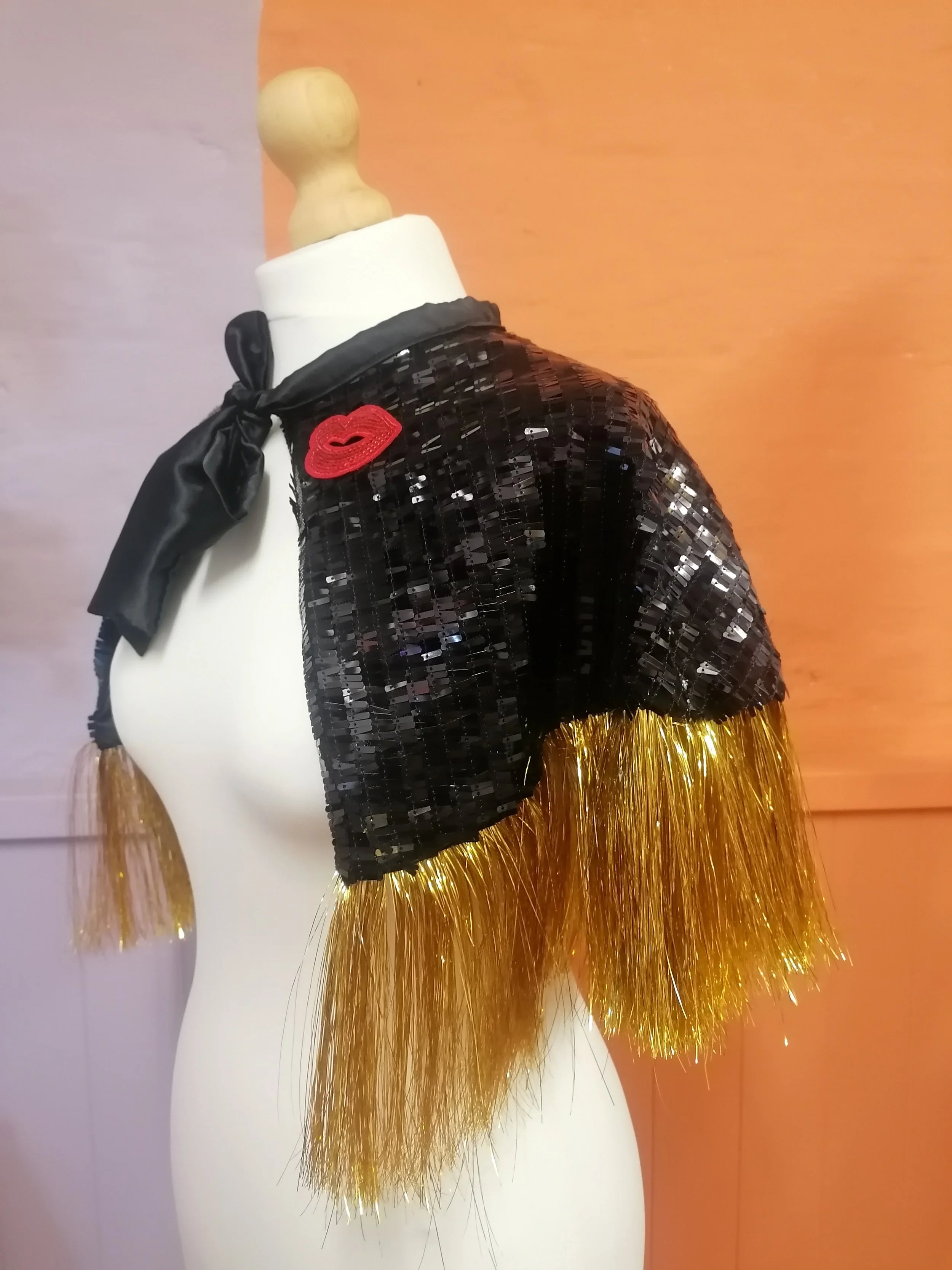Black sequin 'Kiss' cape with gold tinsel trim