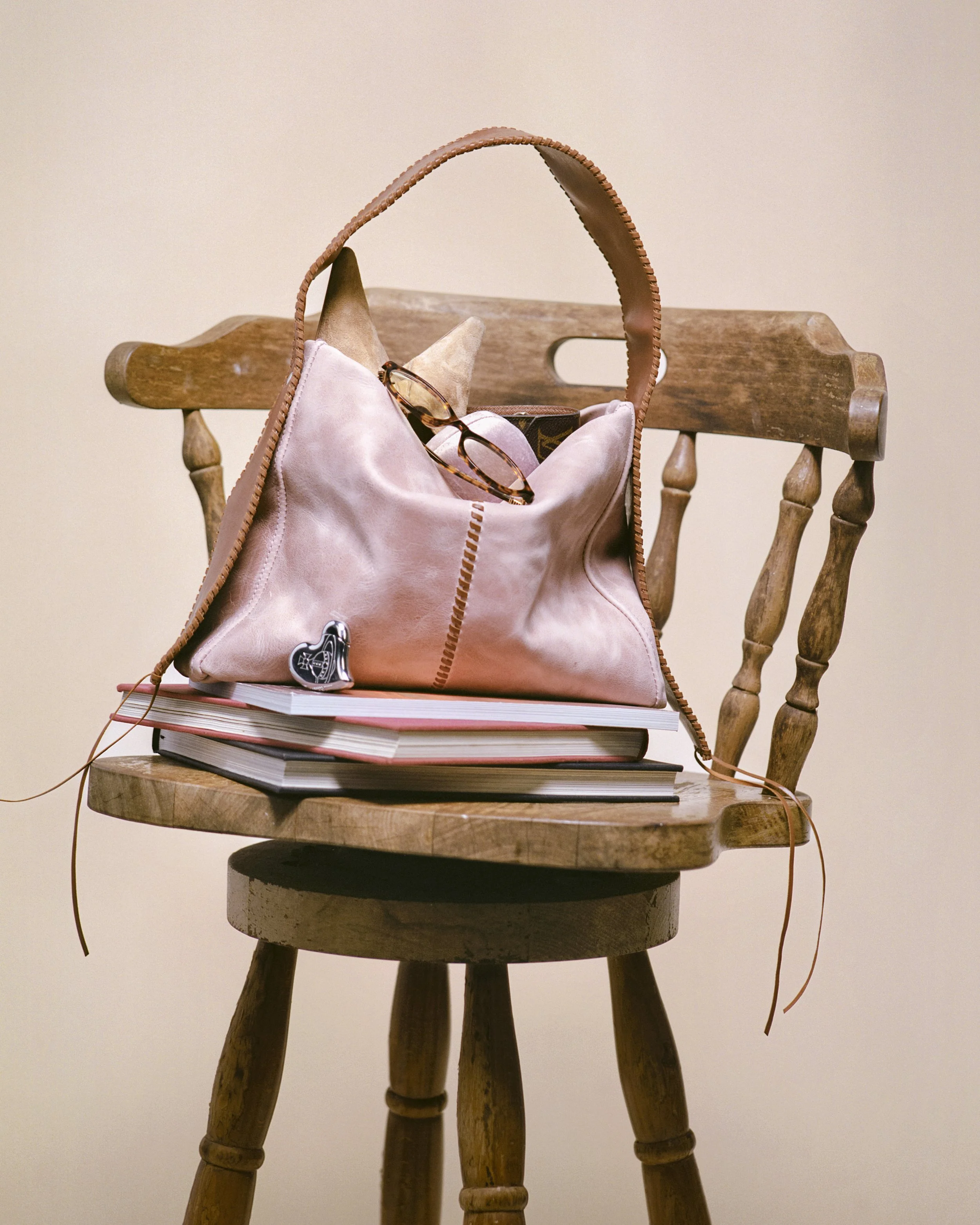 A wooden chair displaying the Vega handbag, styled with everyday items, showcasing the bag’s design and functionality.