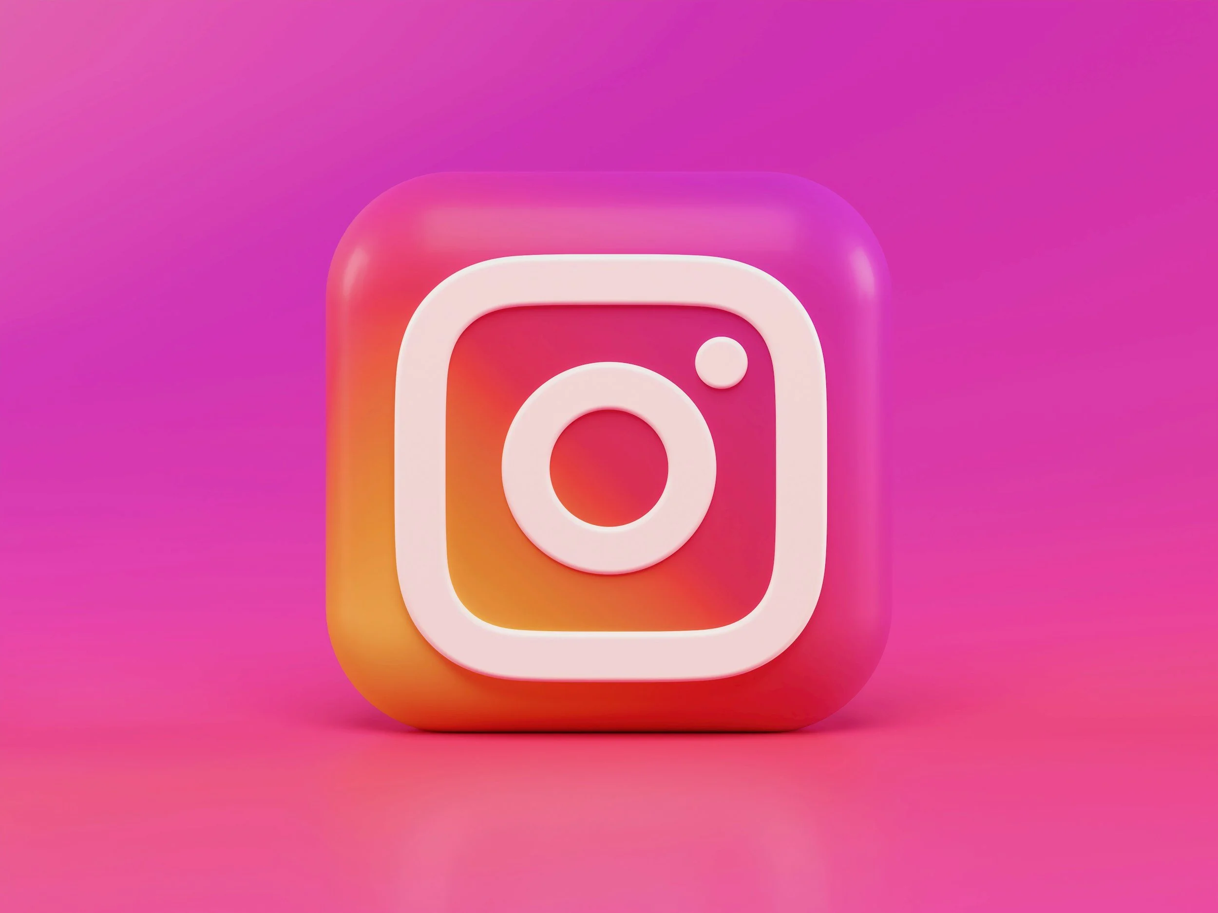 3D pink, orange, and purple Instagram logo icon on a pink gradient background.