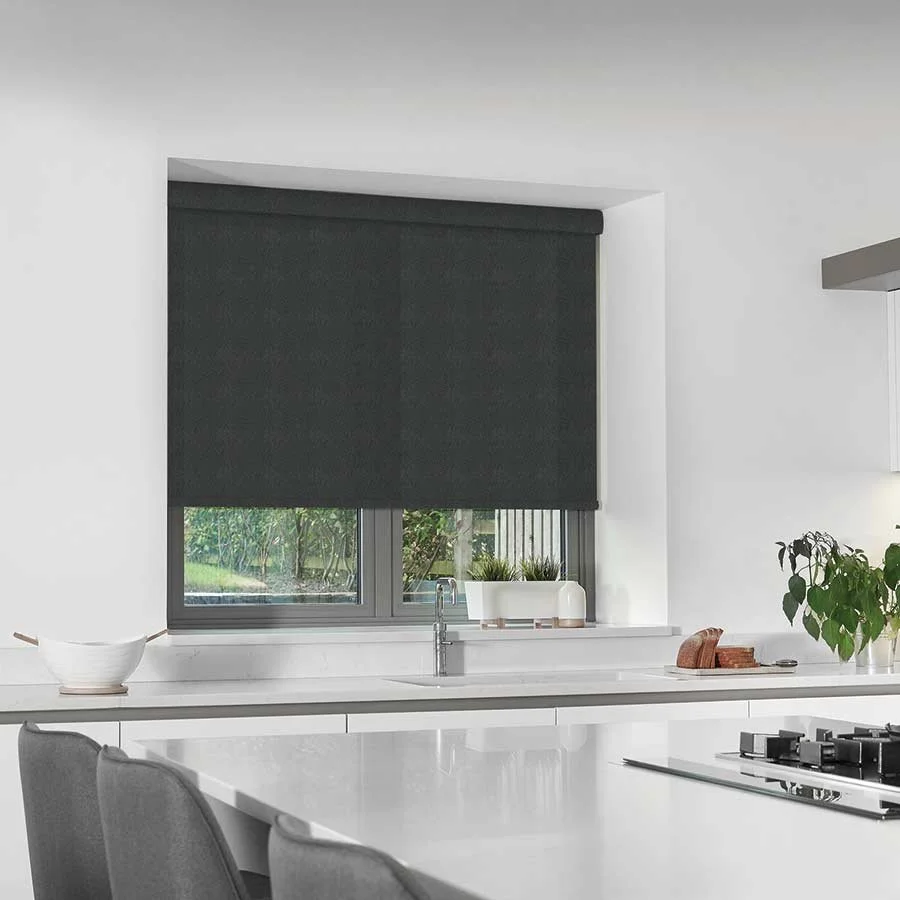 Modern kitchen with white countertops, dark window blinds, a window with a view to a garden, a cookbook, a potted plant, and a white bowl.