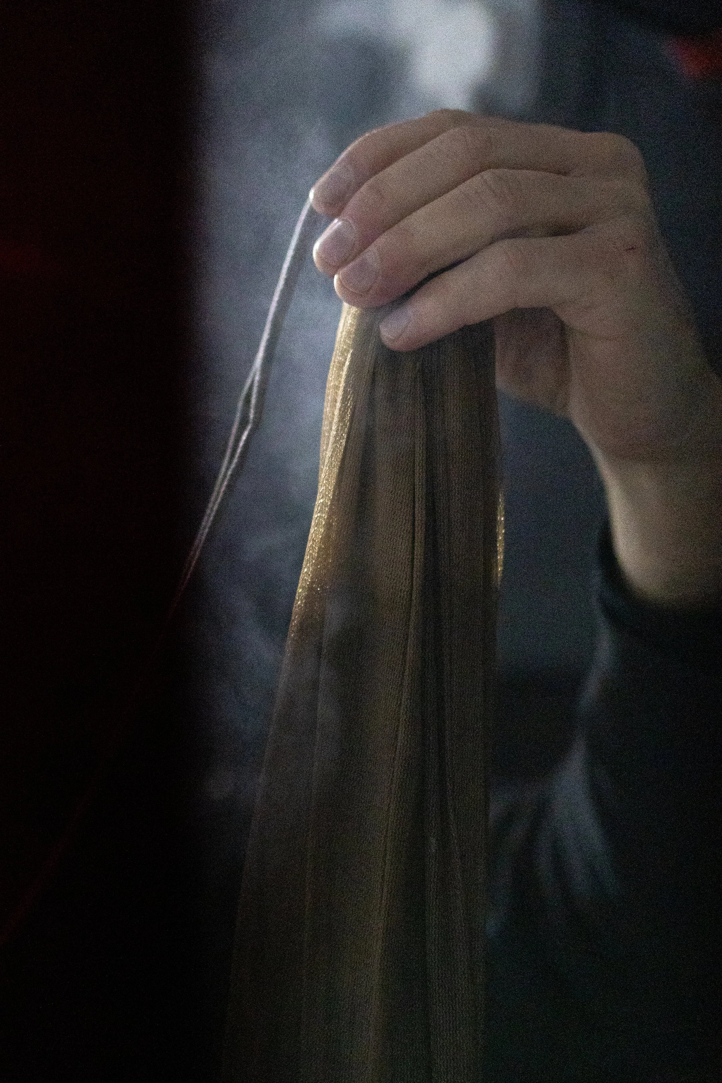 A person's hand holding a zipper on a backpack with a dark background.