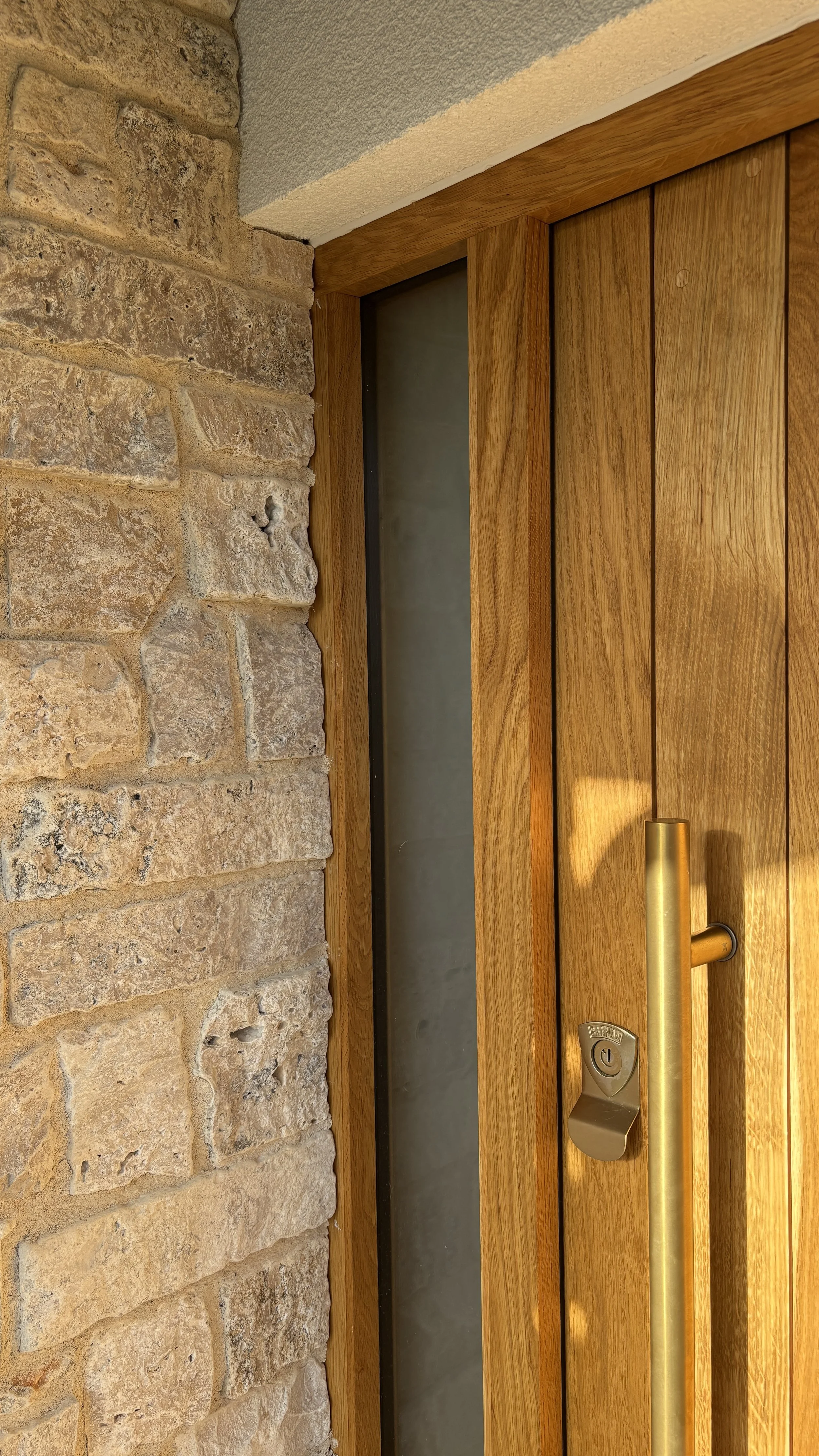 Wooden door with a vertical handle and lock, framed by brick wall and ceiling