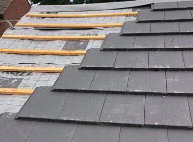 Close-up of a roof with black slate tiles and wooden battens.