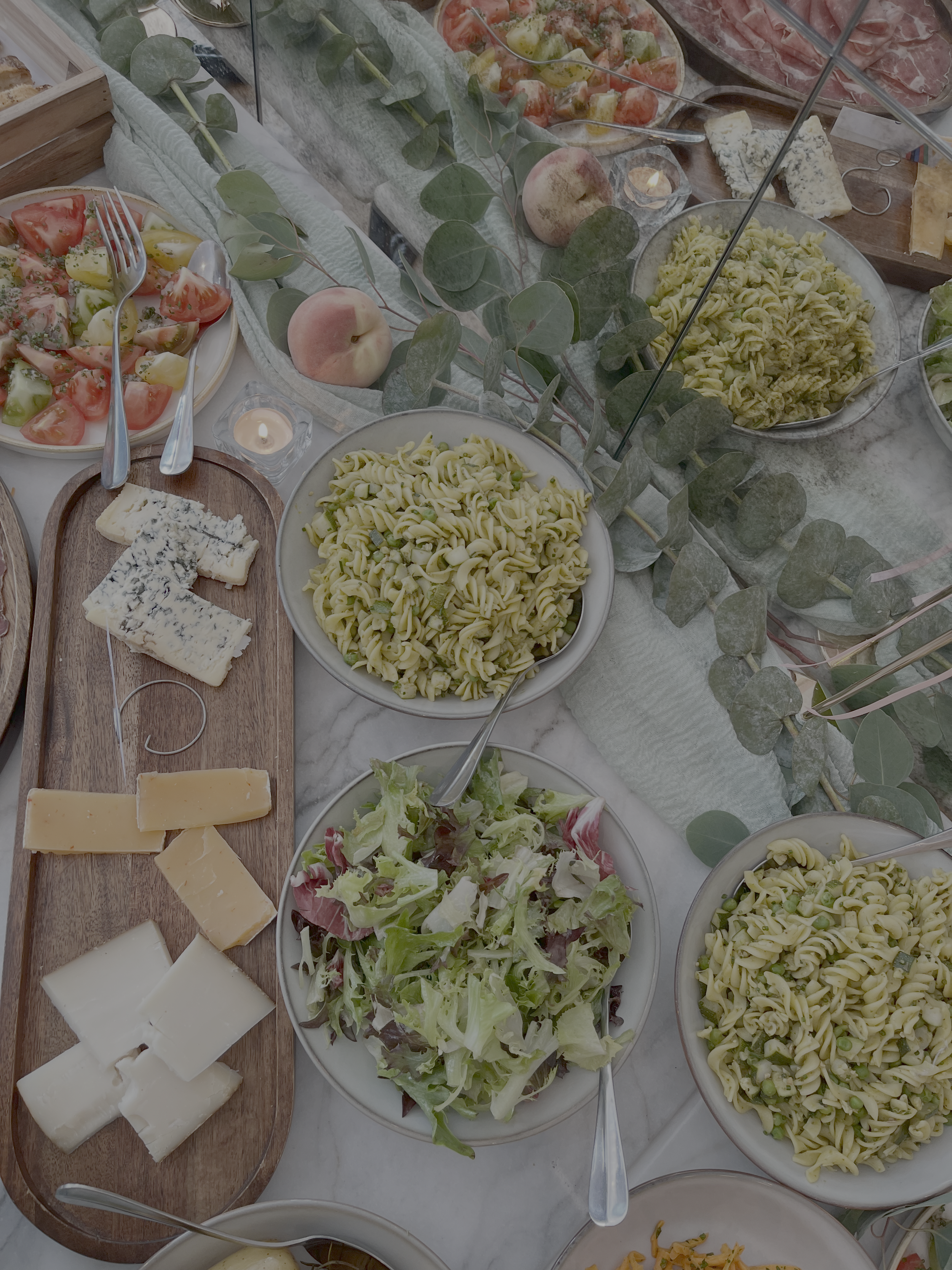 A variety of pasta salads, cheese, and fresh vegetables on a buffet table.