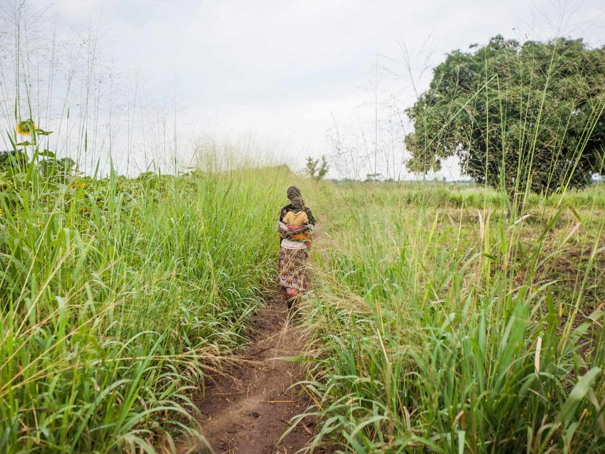 Woman and her child walking in a field.