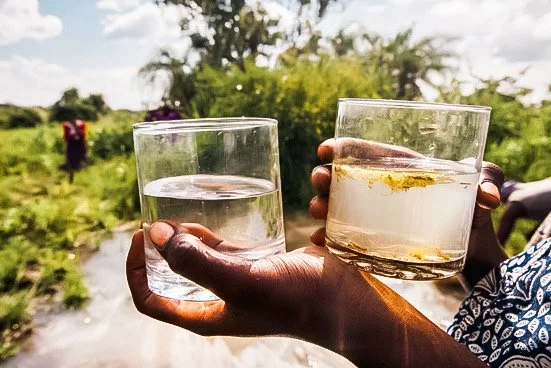 boy holding two water glasses.