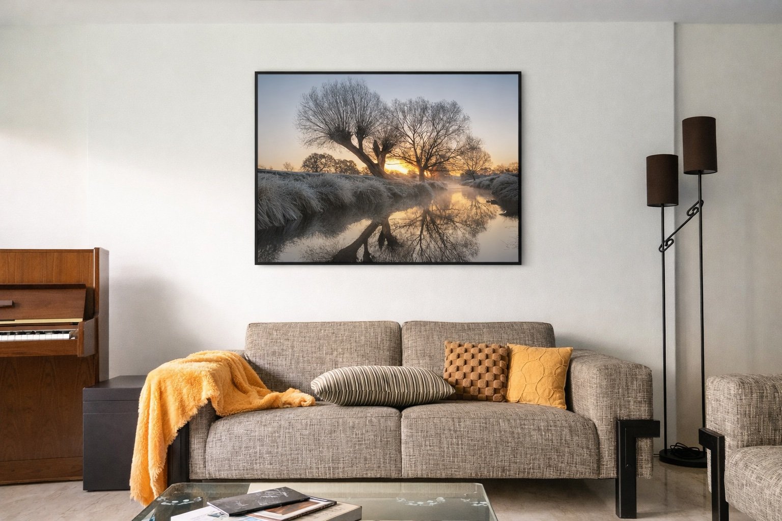 Living room with a beige couch, decorative pillows, a blanket, a glass coffee table with magazines, a framed nature photo on the wall, a floor lamp, and a keyboard piano.