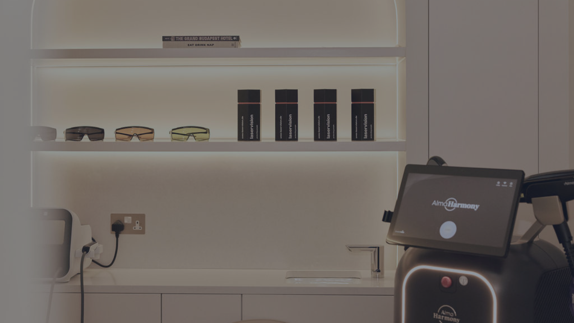 A black and gray built-in closet with gold handles in a corner of a room, with hardwood flooring and a beige wall.