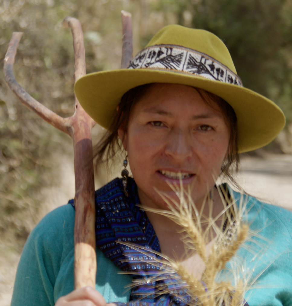Mujer con sombrero amarillo, sosteniendo un lago de madera y rodeada de naturaleza.
