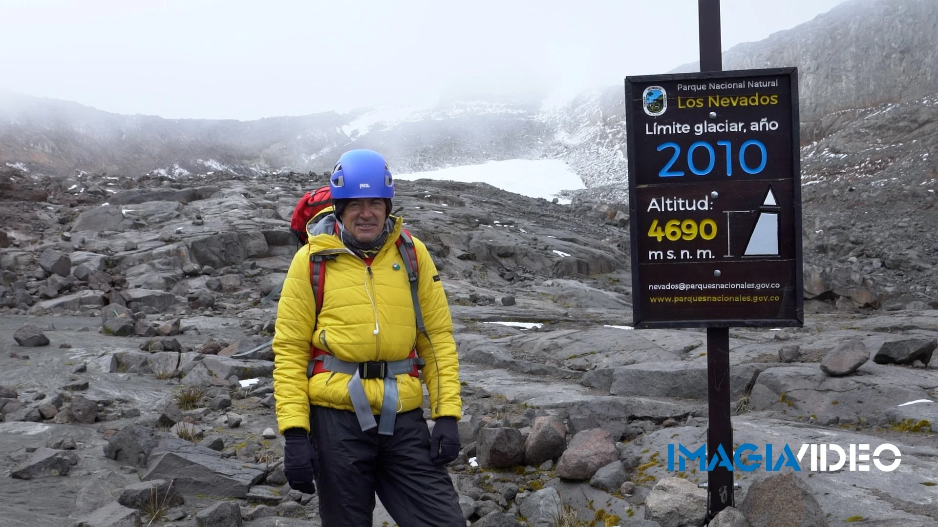 Persona con equipo de alpinismo en la cima del glaciar Los Nevados, en el Parque Nacional Natural Los Nevados, con cartel que indica la fecha del límite glaciar en 2010 y la altitud de 4690 metros sobre el nivel del mar