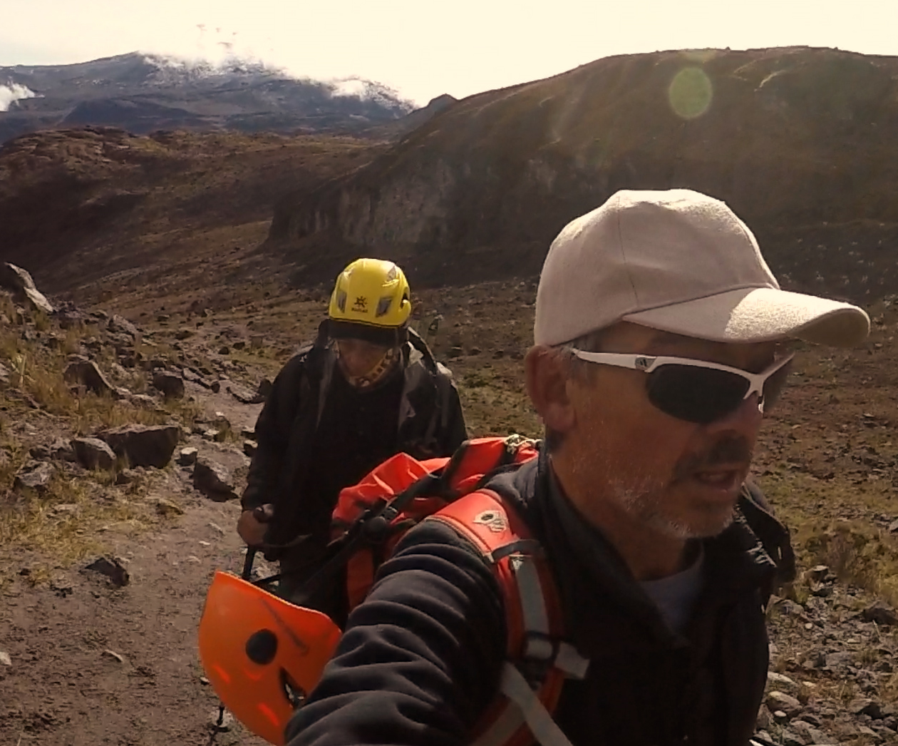 Dos personas caminando por un sendero en un paisaje montañoso mientras practican senderismo o escalada en un área natural.