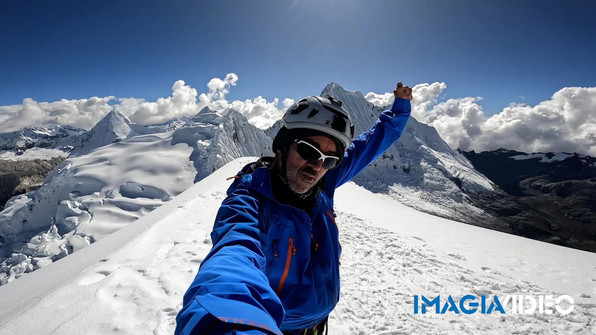 A hombre en equipo de escalada en la nieve en la cordillera de los Andes, con montañas y cielo despejado en el fondo.