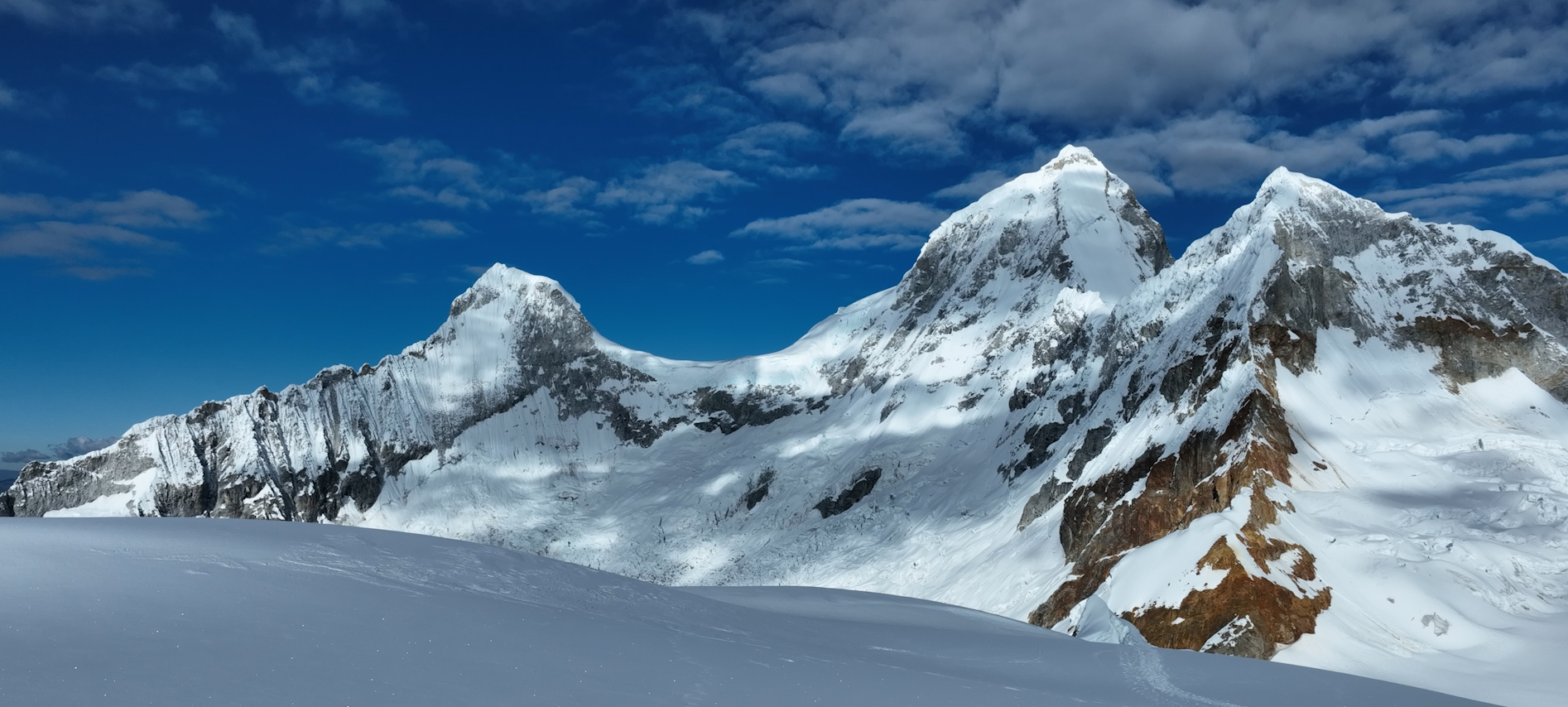 Montañas cubiertas de nieve bajo un cielo azul con nubes.