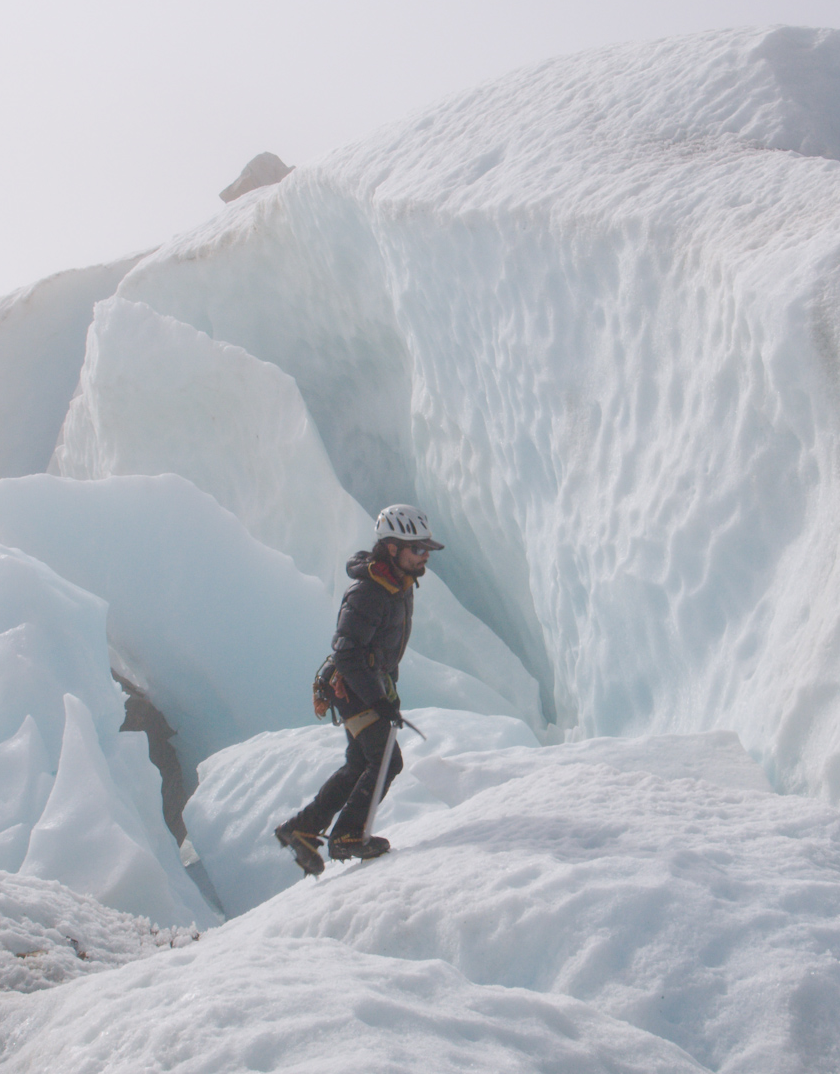 Aventurero con casco y equipo de escalada en hielo atravesando un paisaje de hielo y nieve en una expedición en la nieve.