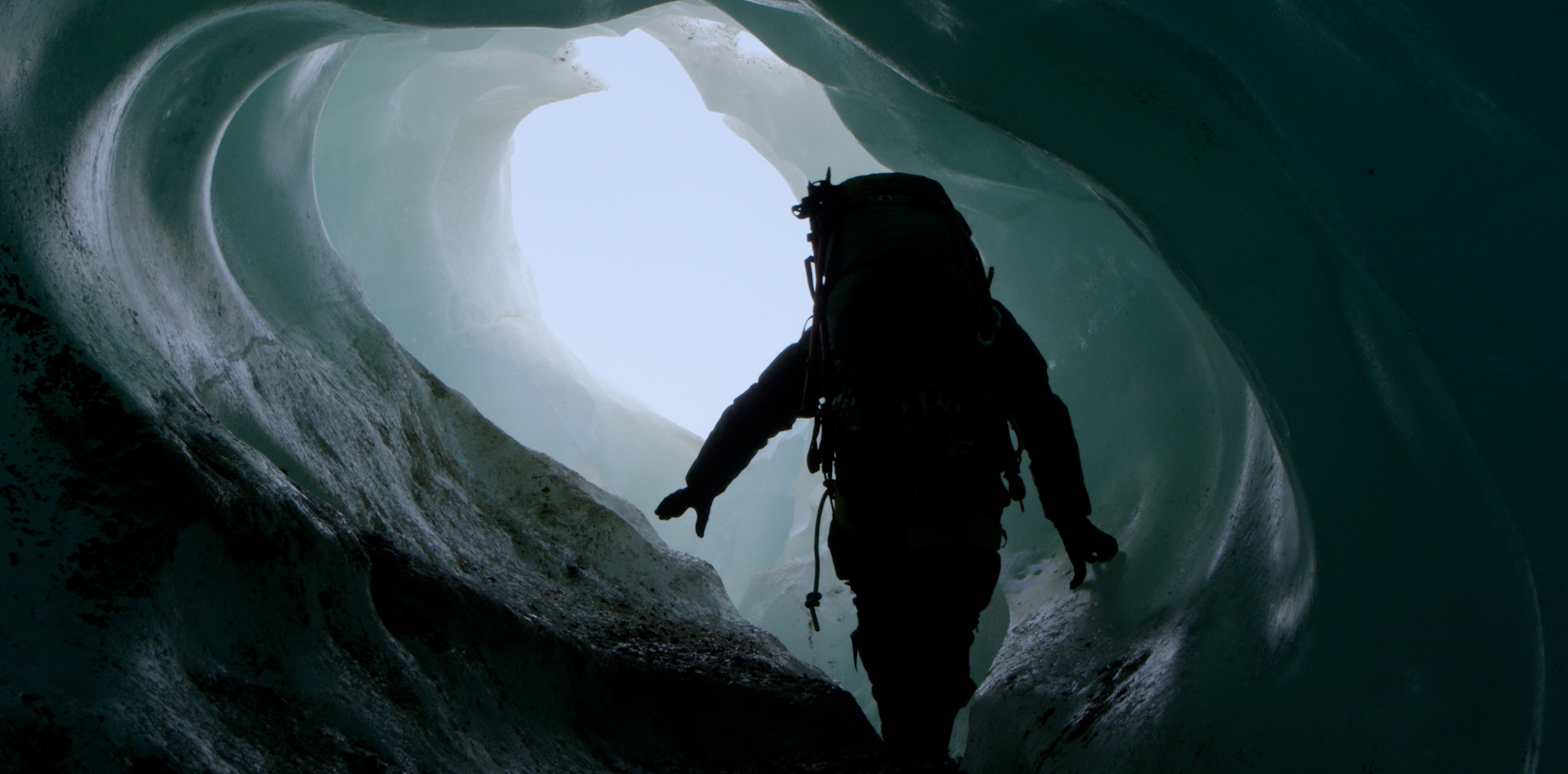 Persona con equipo de exploración explorando una cueva de hielo.