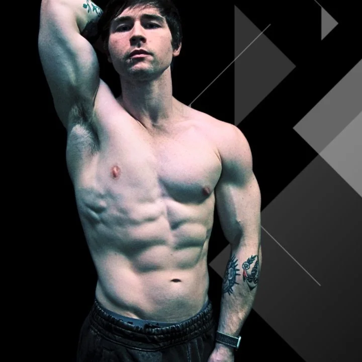 A shirtless young man with tattoos poses against a black and gray geometric background.