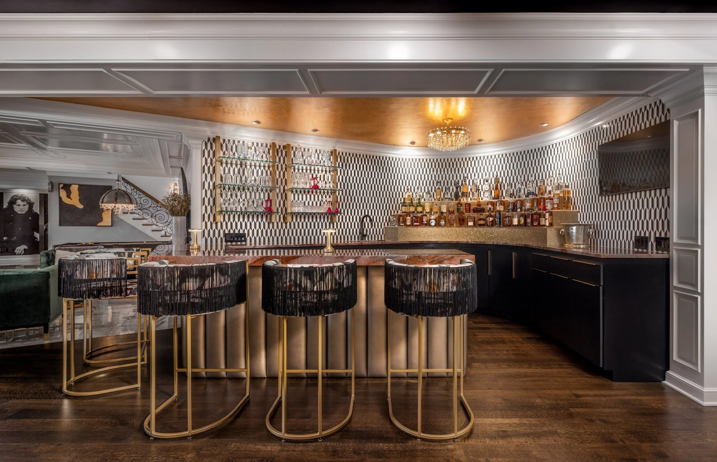 Basement cocktail bar with black and white tile, a gold ceiling and fringed black bar stools