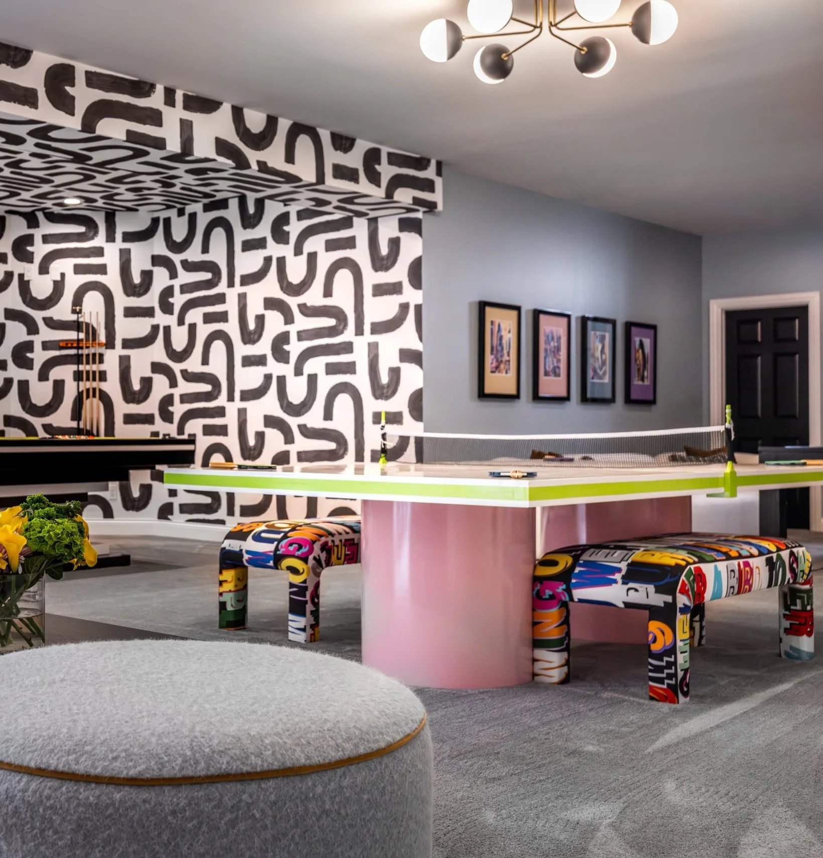Basement game room with ping pong table, graphic black and white wallpaper and patterned benches