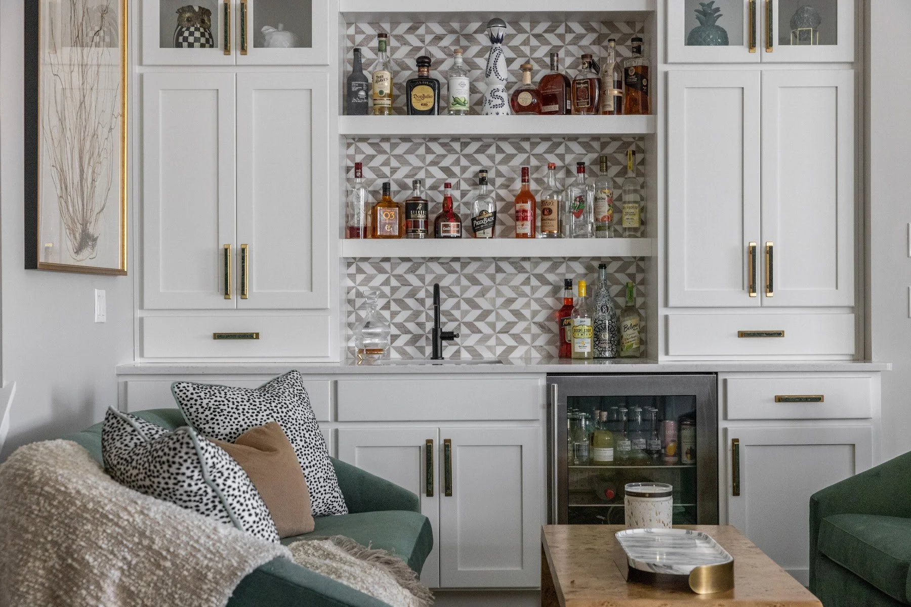 White home bar with glass shelves for bottles, geometric tile backsplash and an under-counter beverage fridge