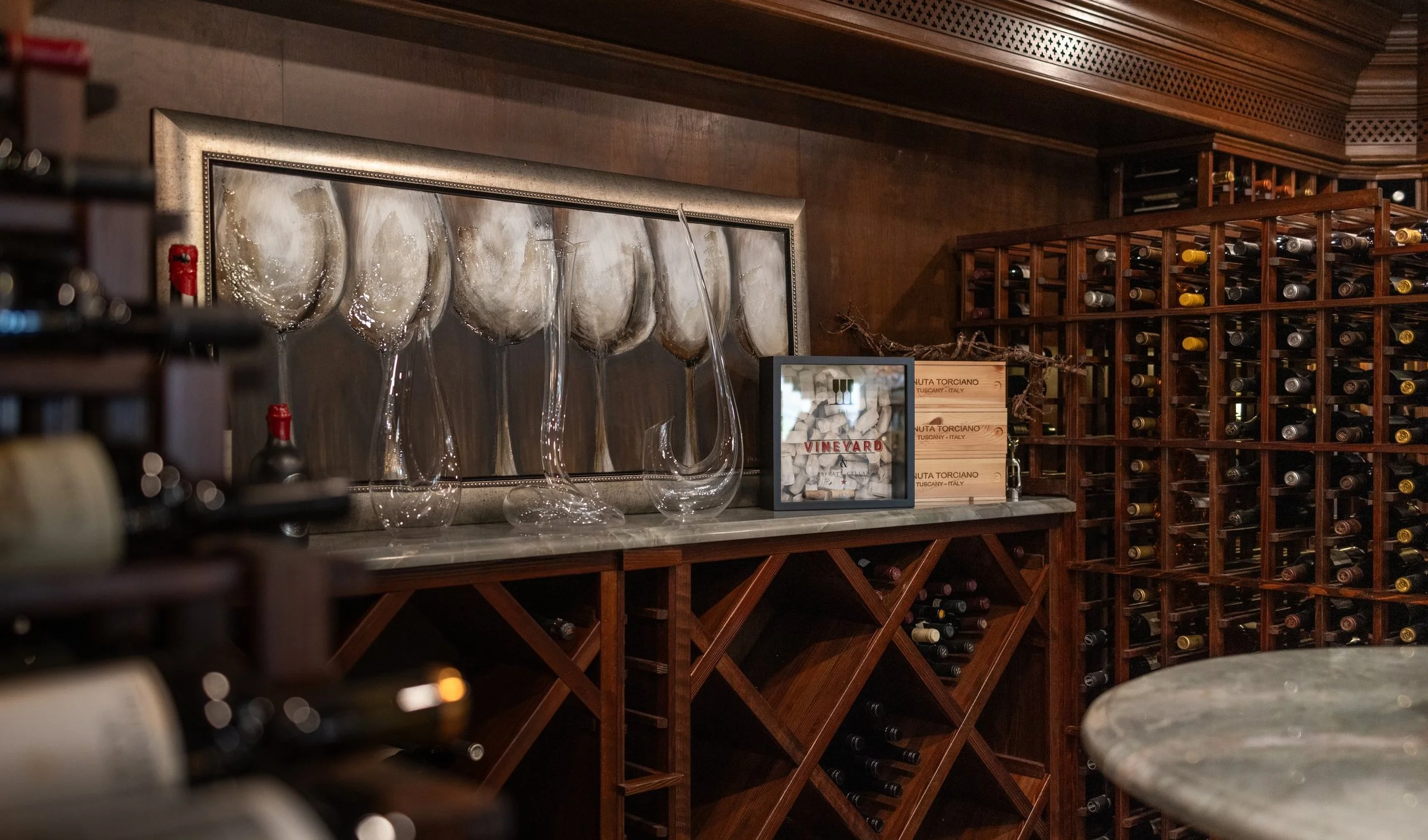 Wine cellar tasting counter with decanters, framed art and diamond wine bins below