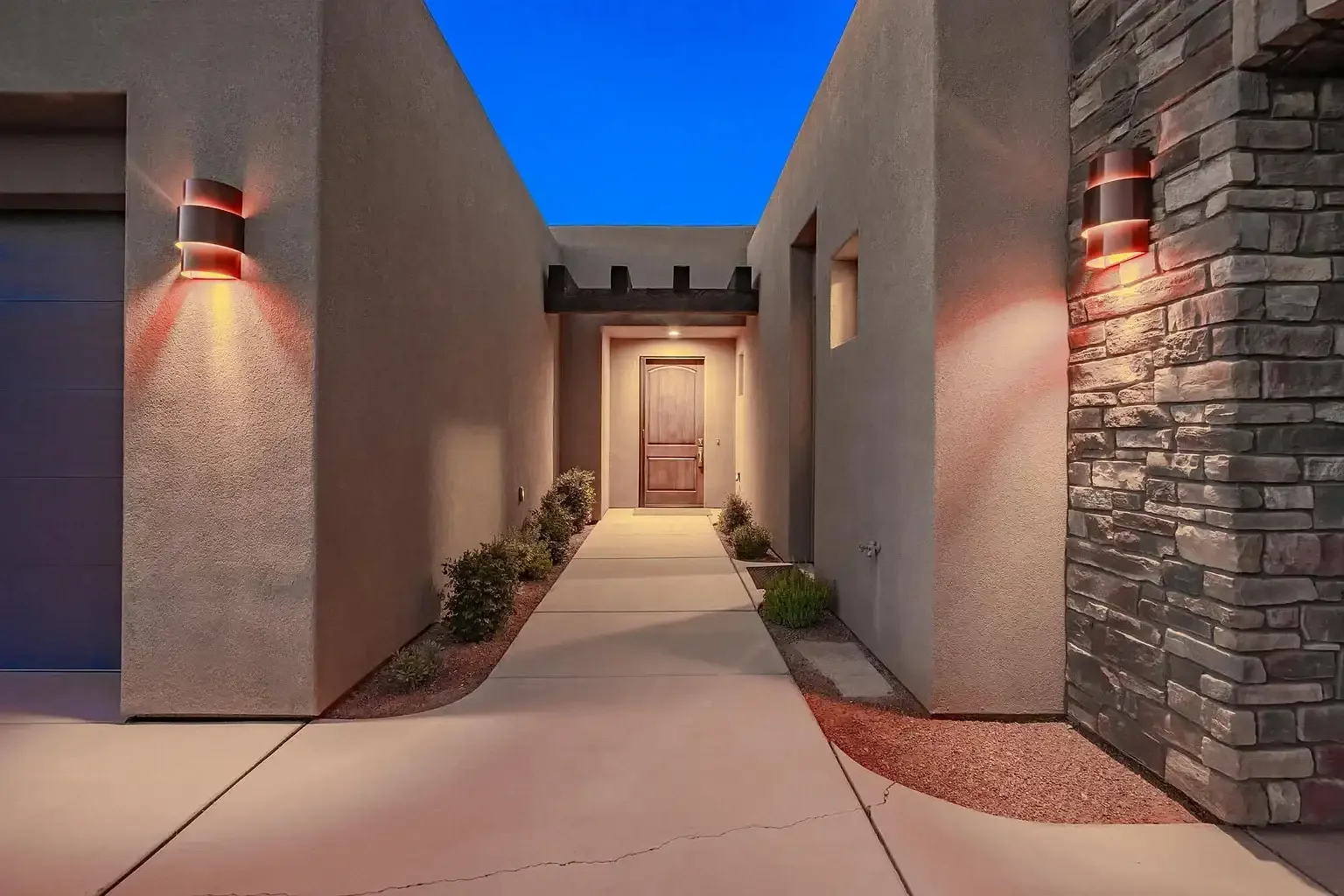 Illuminated entryway of luxury desert home with stucco walls and wood front door, Southern Utah