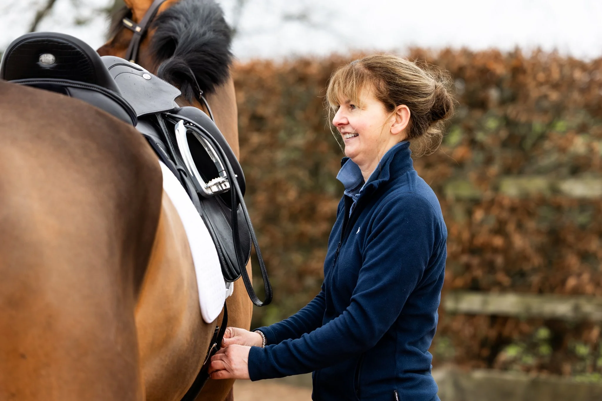 Master Saddle Fitter Charlotte Fountain carefully adjusting a saddle on a horse to ensure proper fit.
