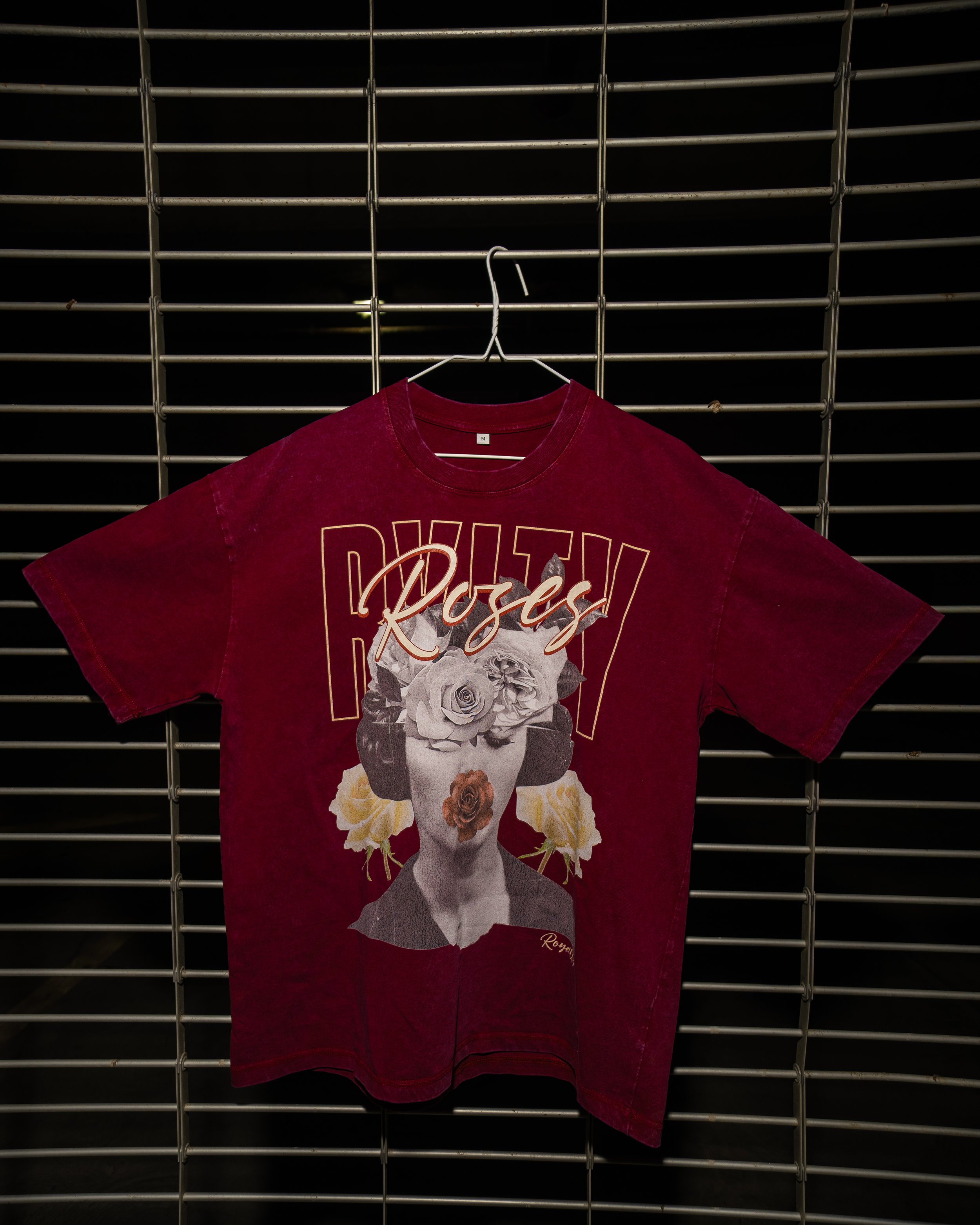 Red T-shirt with floral graphic and the word 'Royale' hanging on a wire grid.