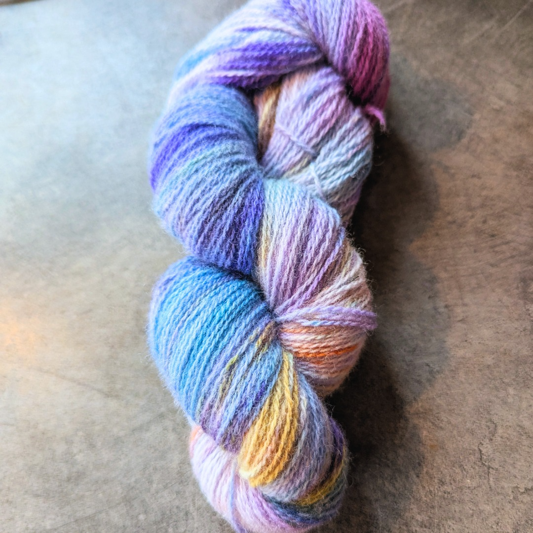Colorful skein of variegated yarn on a gray surface.