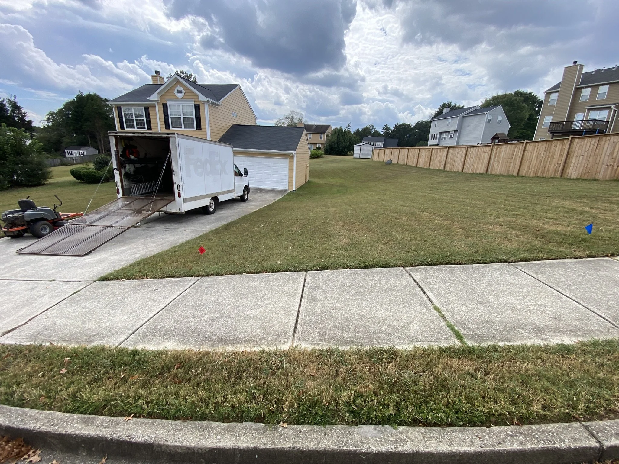 Service truck with equipment ramp positioned in a residential driveway for property maintenance operations