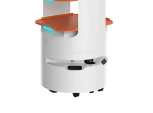 Close-up of a robotic or automated cleaning or scanning device, showing white and orange parts with sensors at the bottom.