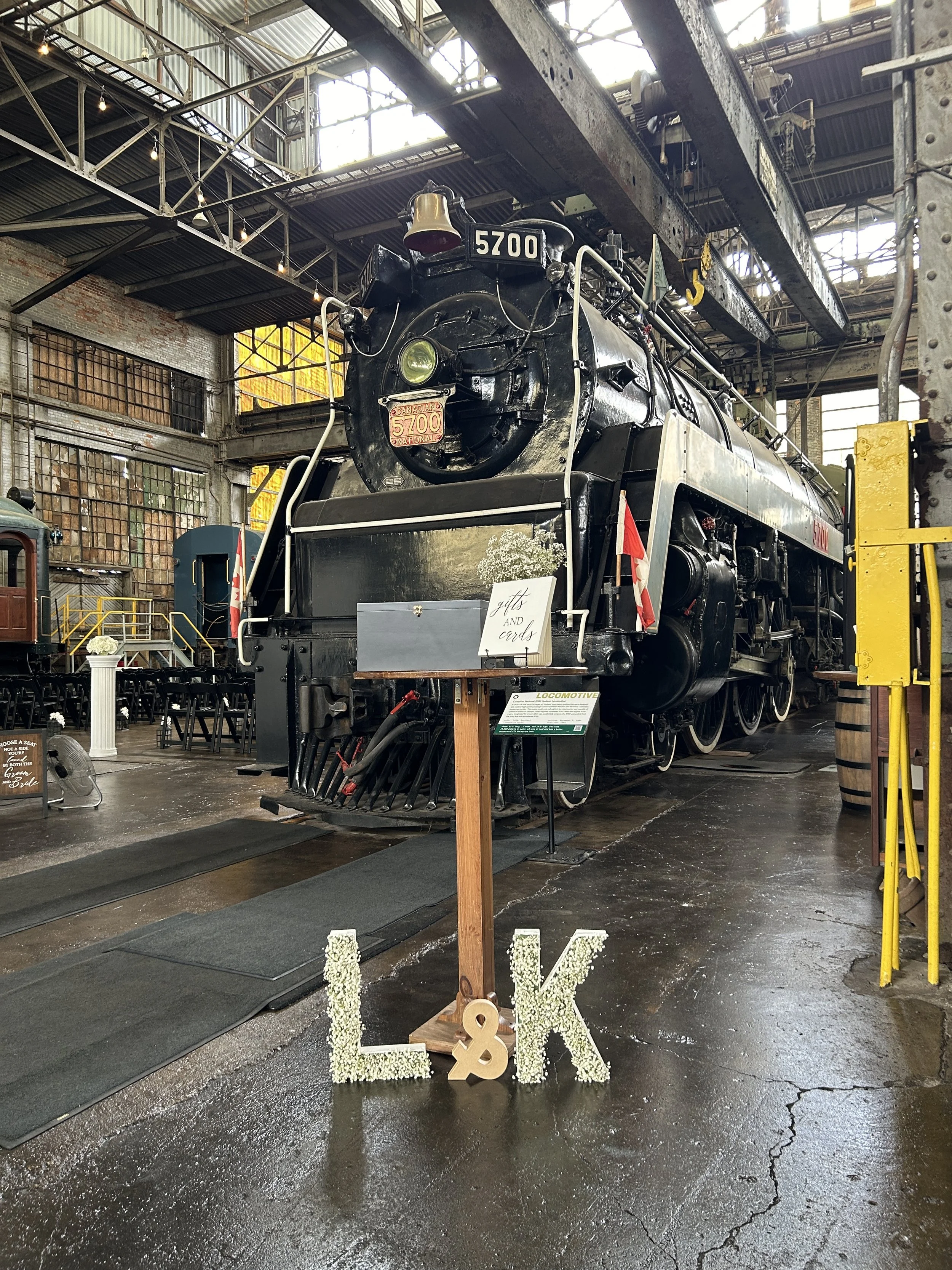Wedding setup inside the Elgin County Railway Museum with the Hudson Steam Locomotive No. 5700 in the background and “L&K” letters displayed