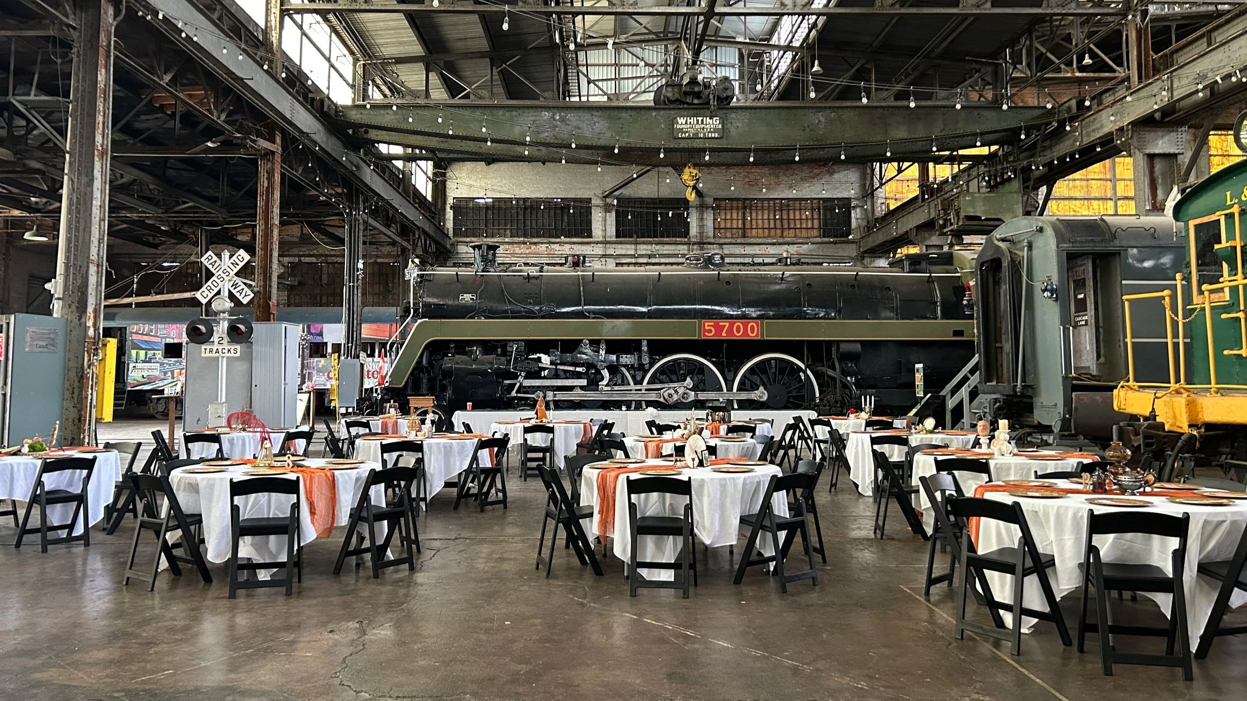 Wedding setup inside the Elgin County Railway Museum with tables arranged and the Hudson Steam Locomotive No. 5700 visible in the background