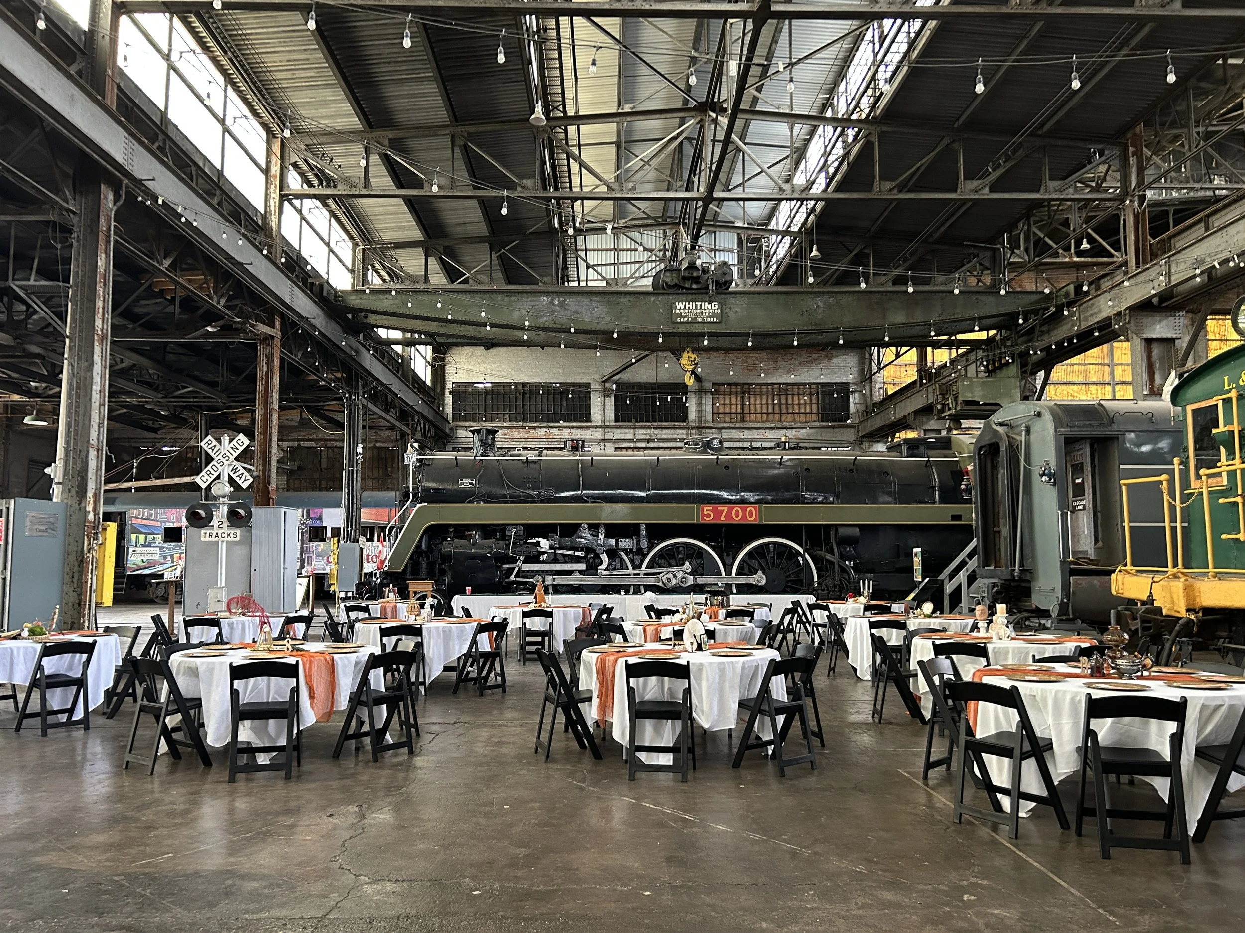 Wedding setup inside the Elgin County Railway Museum with tables arranged and the Hudson Steam Locomotive No. 5700 visible in the background